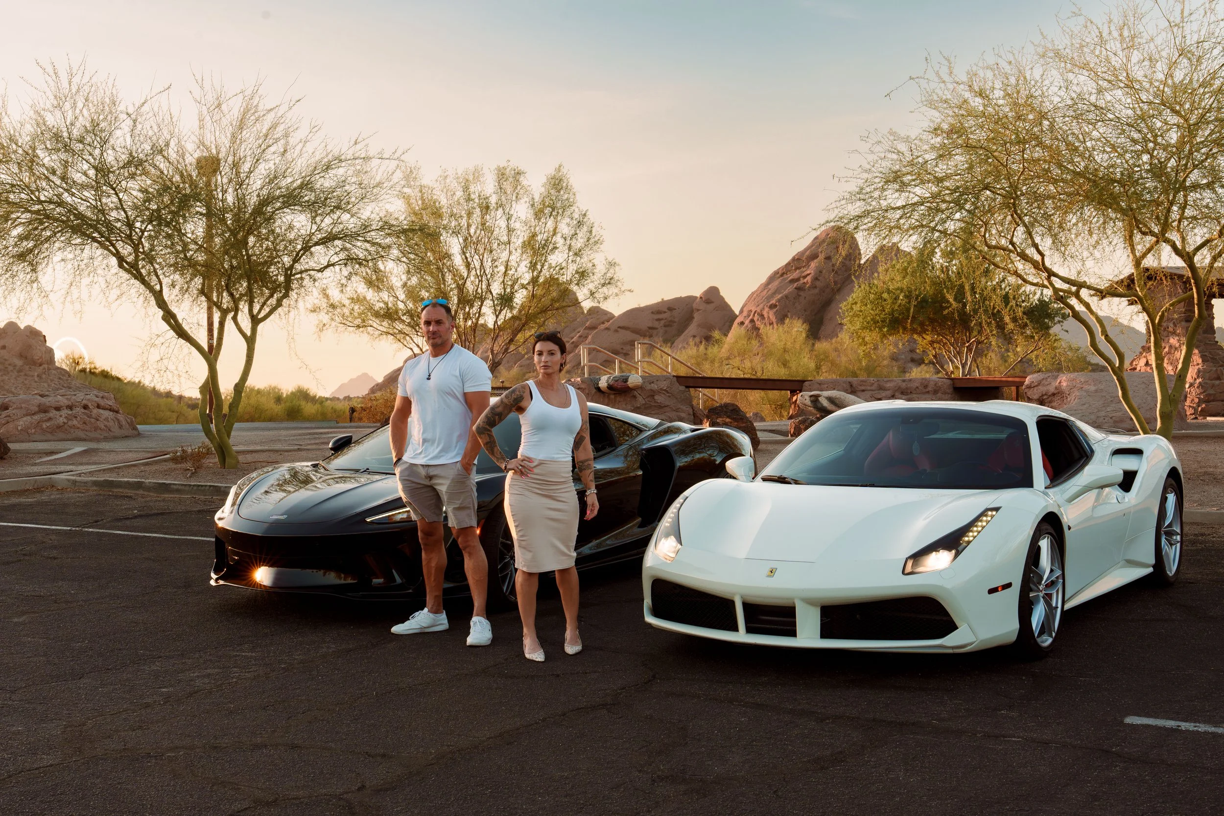 Business partners standing between a Ferrari and McLaren during sunset in Phoenix
