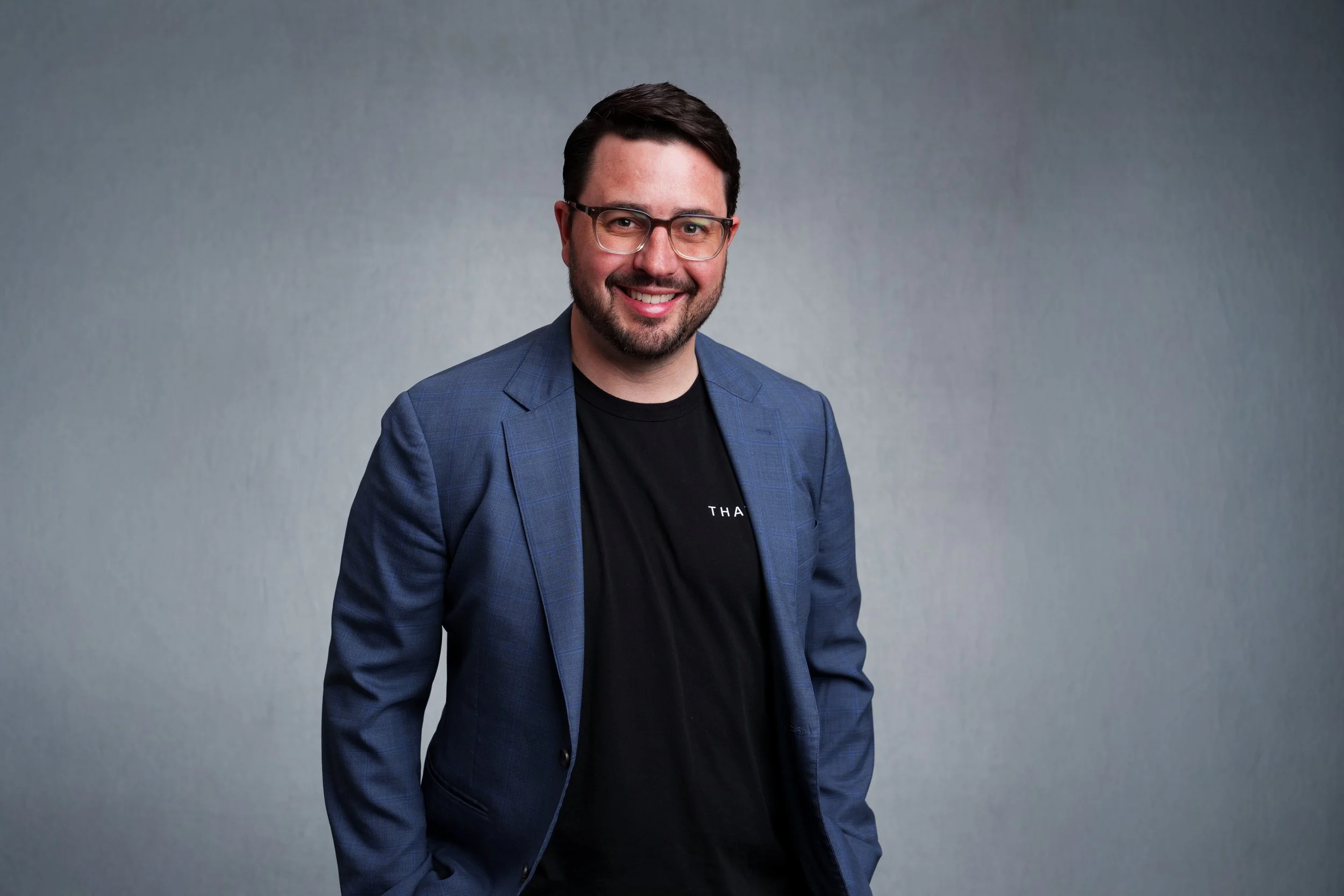 Professional corporate headshot of a man in a blue blazer and glasses photographed against a gray backdrop in Scottsdale, Arizona.