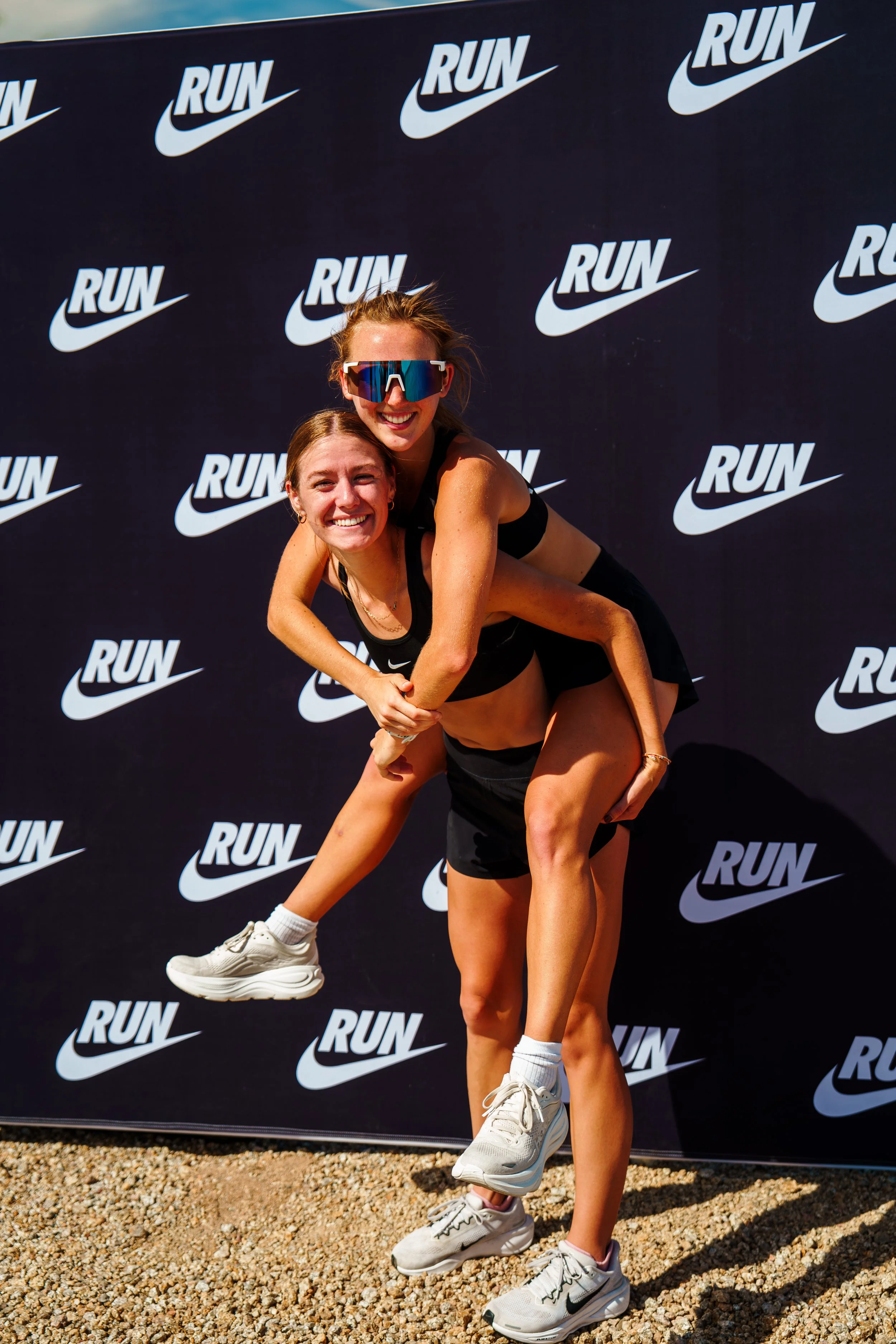 Two runners celebrating in front of the Nike RUN backdrop at Project PR