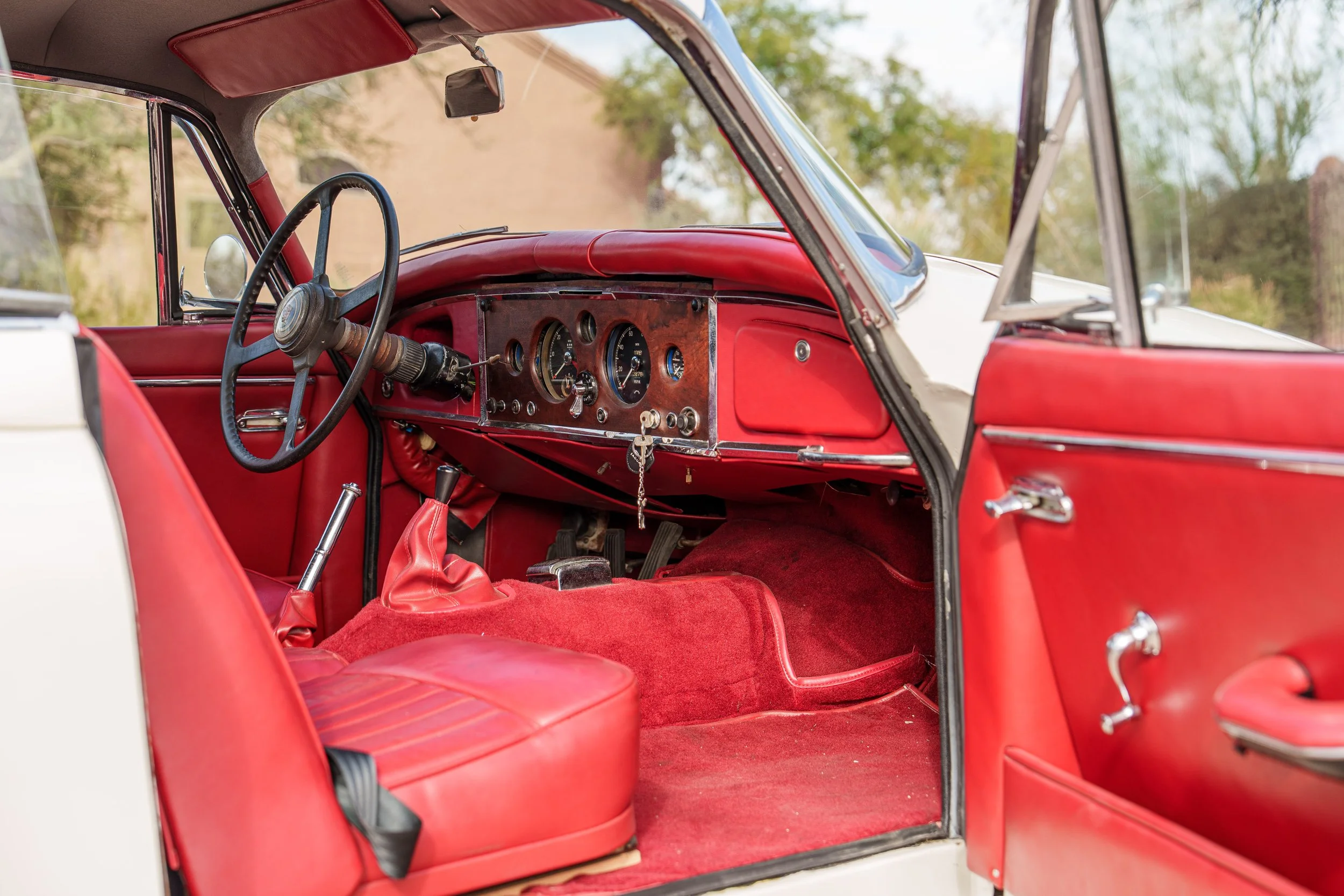 White Jaguar XK150 bodywork with red interior visible through the side window
