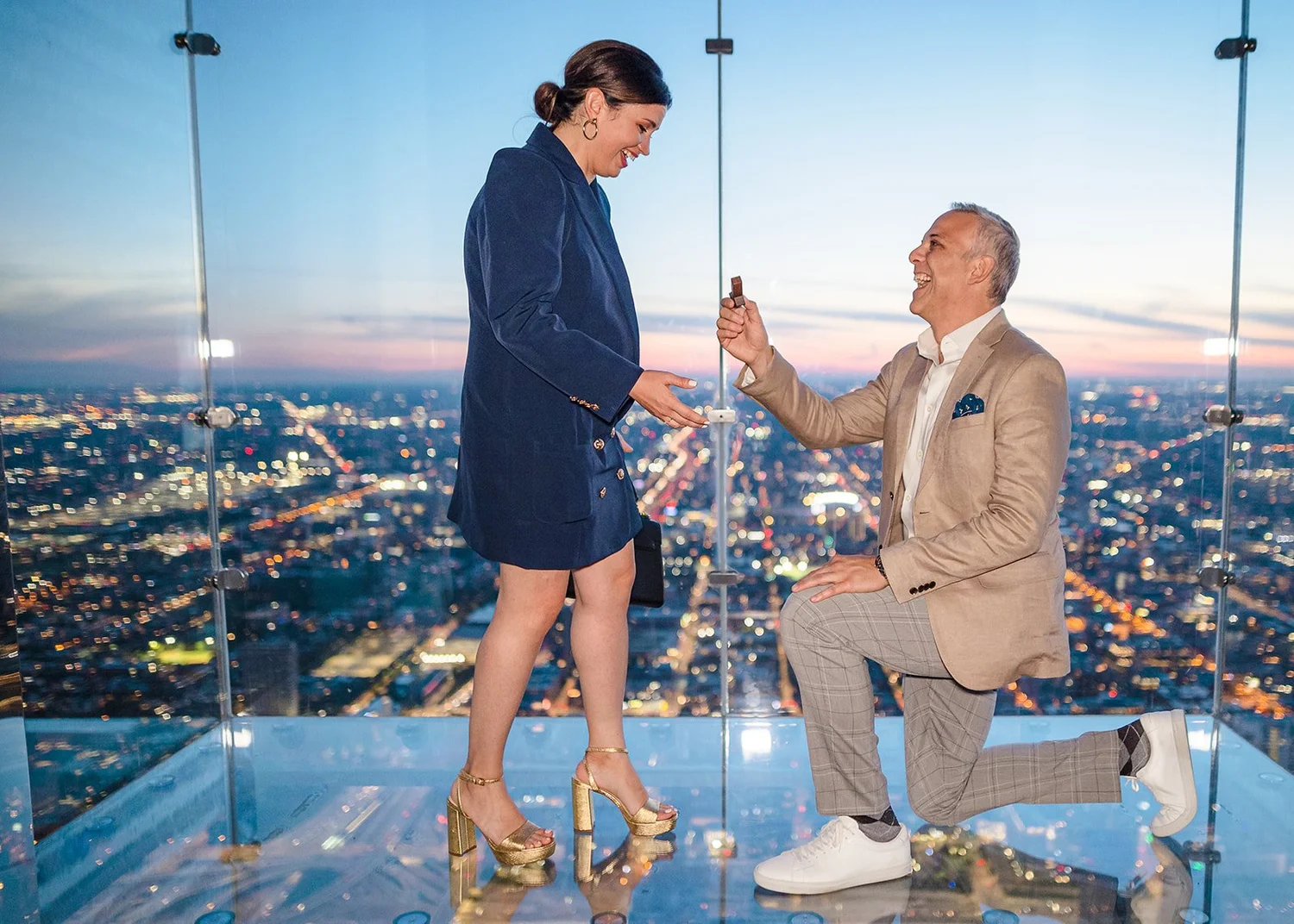 Newly engaged couple admiring ring after surprise proposal at The Bean in Chicago