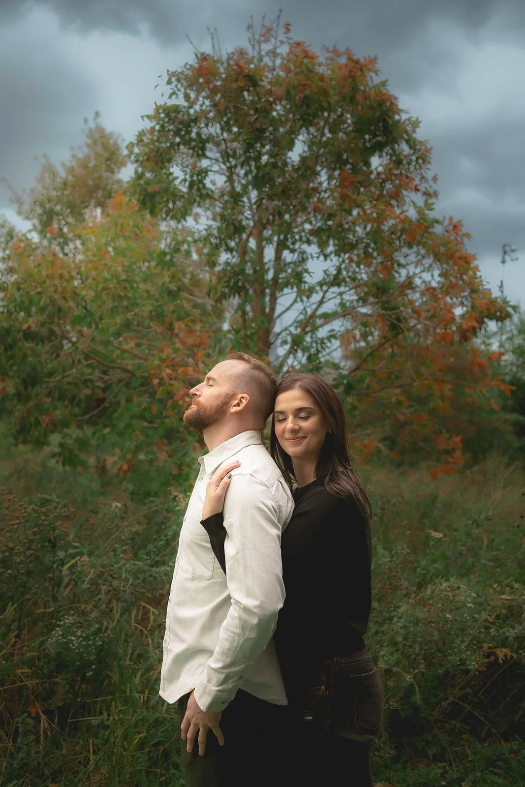 Future bride embracing her husband from behind in front of tree in Chicago's Ping Tom Park