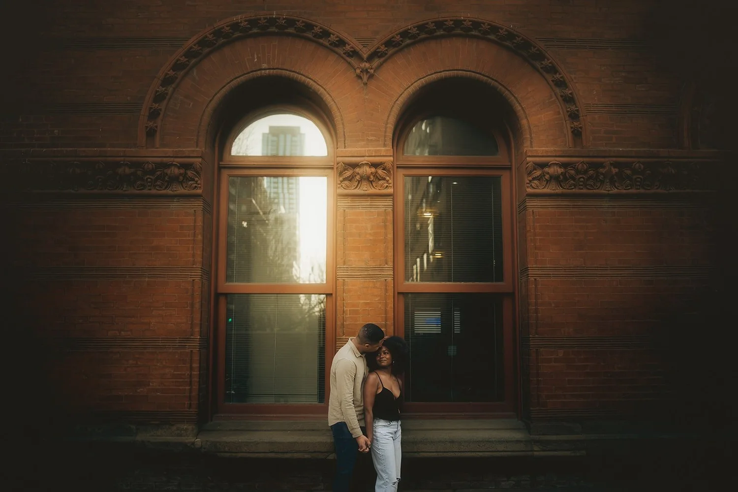 Gritty sunset engagement session at Printer's Row, stylish pose in front of antique, moody building