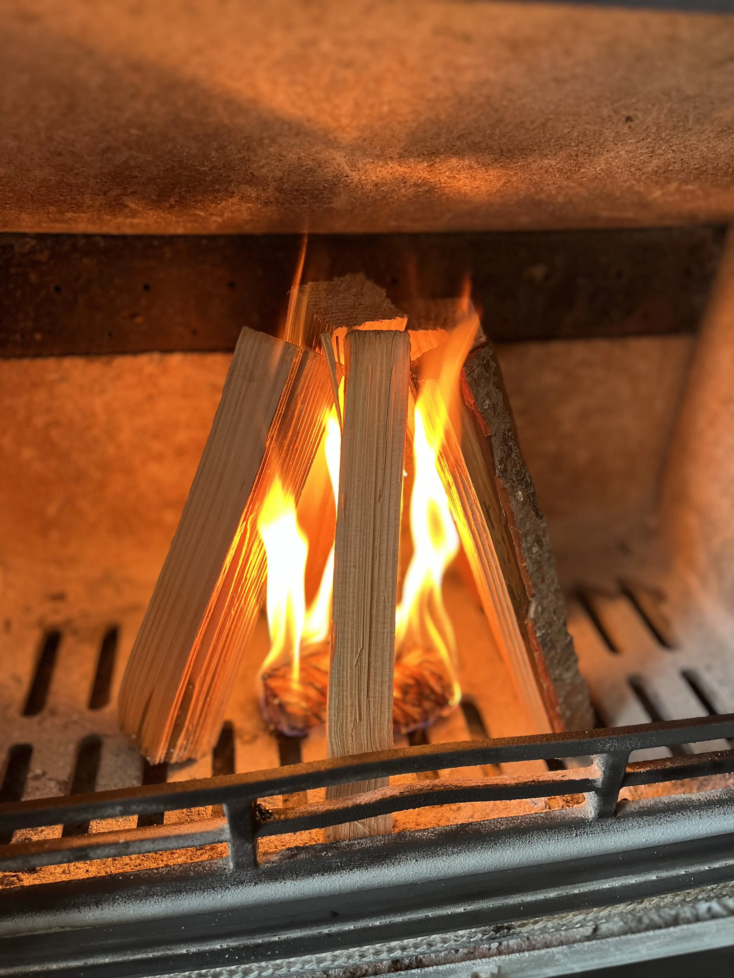 Close-up of a premium Timber Culture eco wood wool firelighter igniting high-quality kindling inside a modern wood-burning stove.