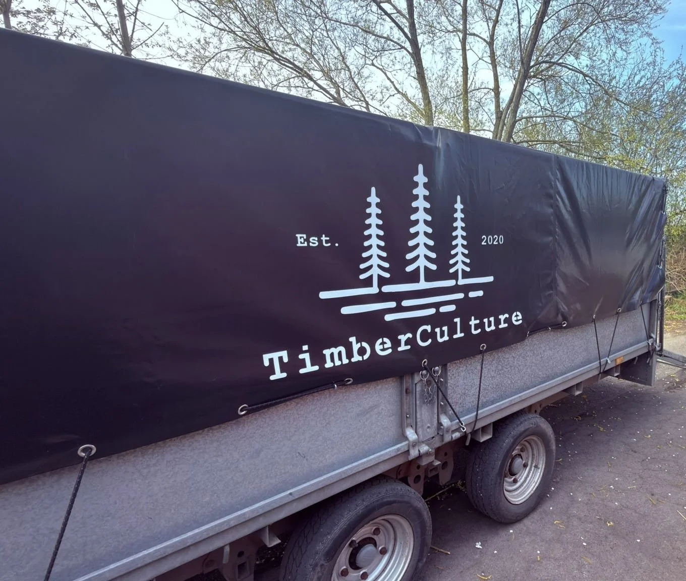 A trailer with a black cover displaying a logo for TimberCulture, featuring three pine trees and the text 'Est. 2020'.