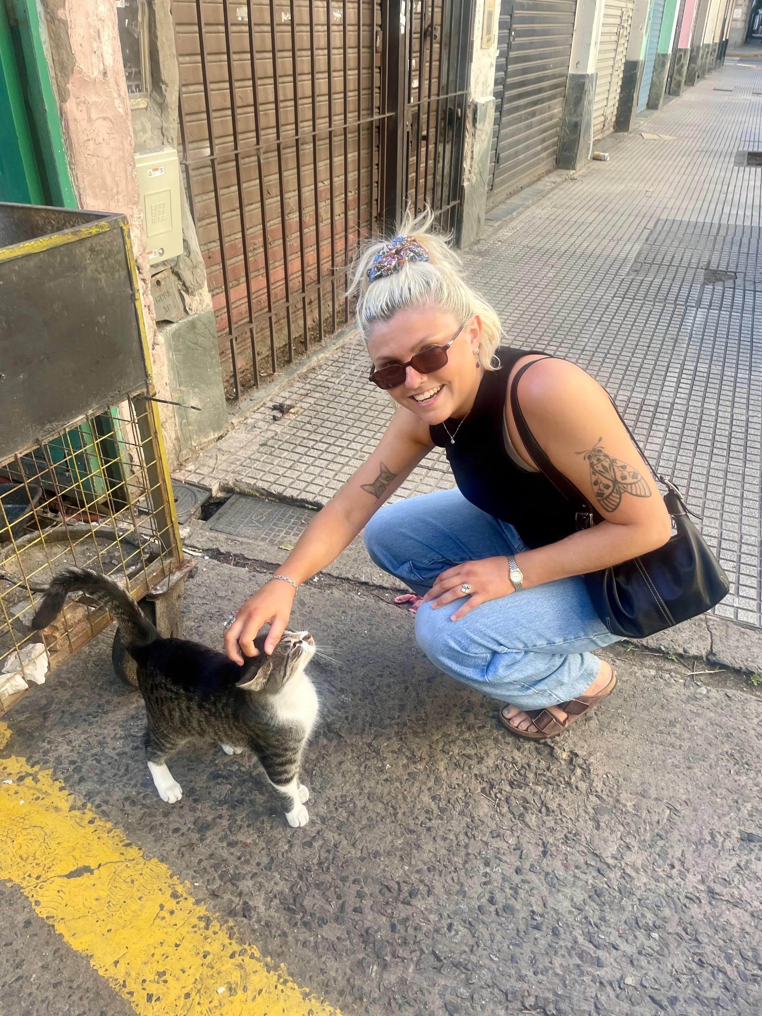 A woman with short blonde hair smiling and petting a kitten