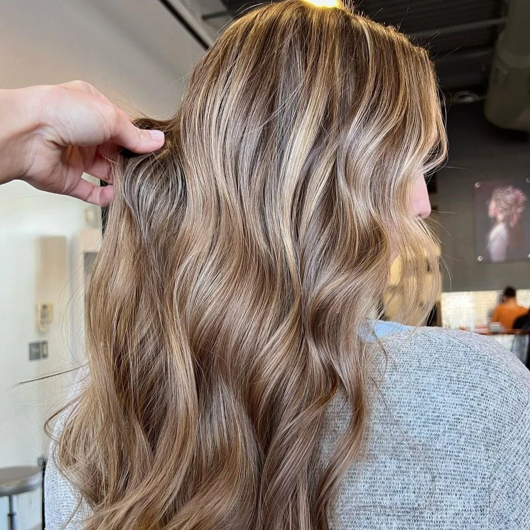 Close-up of a woman with long, wavy, blonde hair with highlights and lowlights.