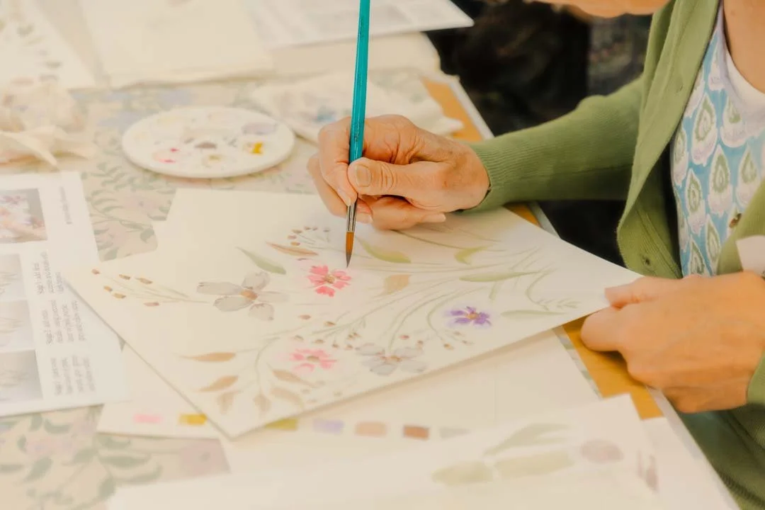 Ladies hands painting watercolour flowers at a watercolour workshop by Illustrator Helen Ridley