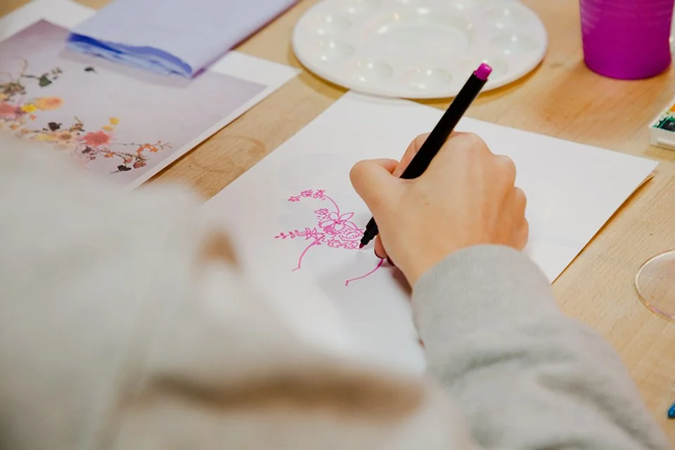 Close up of hand holding a pink pen and doodling flowers at a workshop run by illustrator Helen Ridley