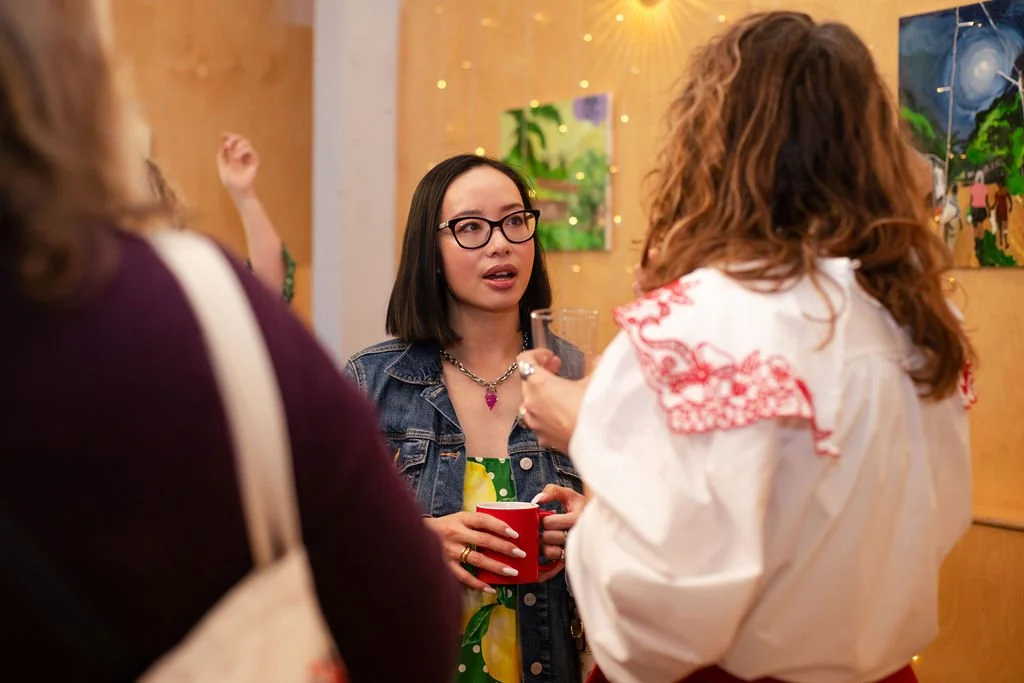 Kendall Marie Platt with curly hair wearing a white blouse speaking with another guest who has dark hair and glasses at the creative networking event in Reading
