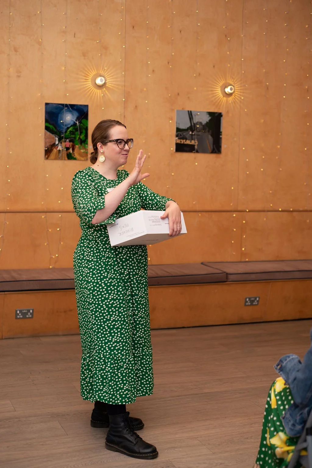 Illustrator Helen Ridley wearing a green dress public speaking to a group of guests at her creative networking event in Reading, UK
