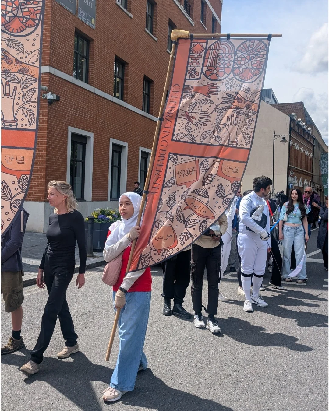 Lady wearing hijab carrying centenary flag through parade in reading
