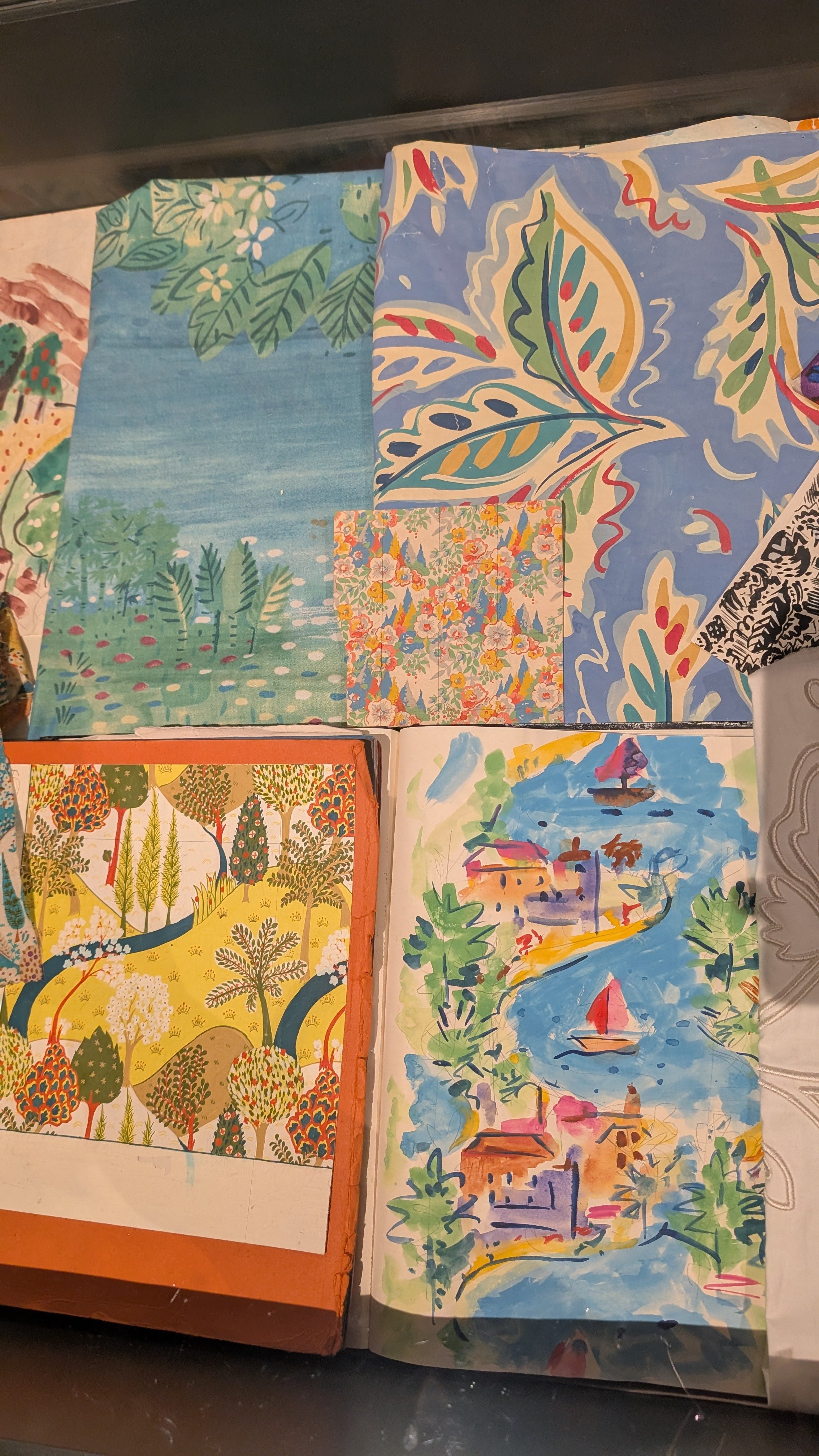 A collection of painted colourful sketchbooks and floral patterned fabric at the Paint Pattern Print exhibition in London