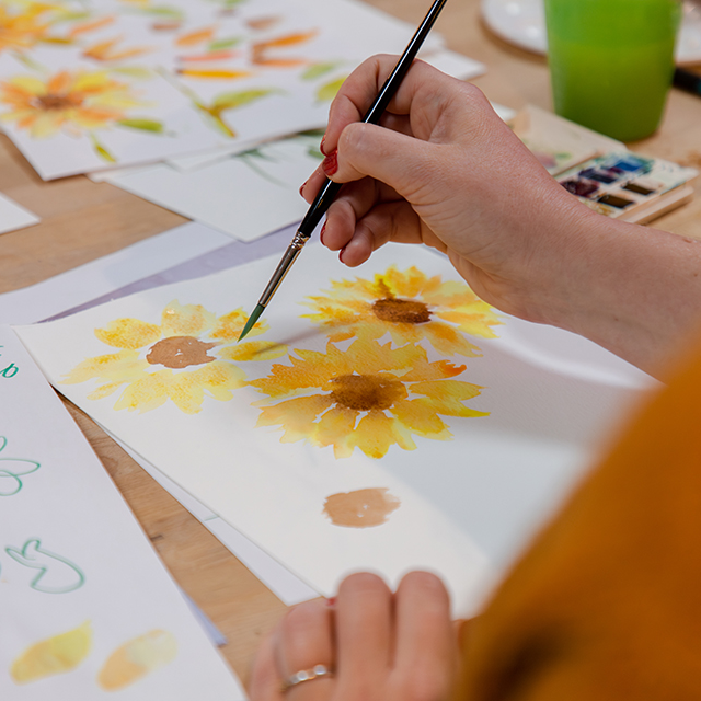 Close up of hand painting watercolour sunflowers at wellness workshop by Helen Ridley