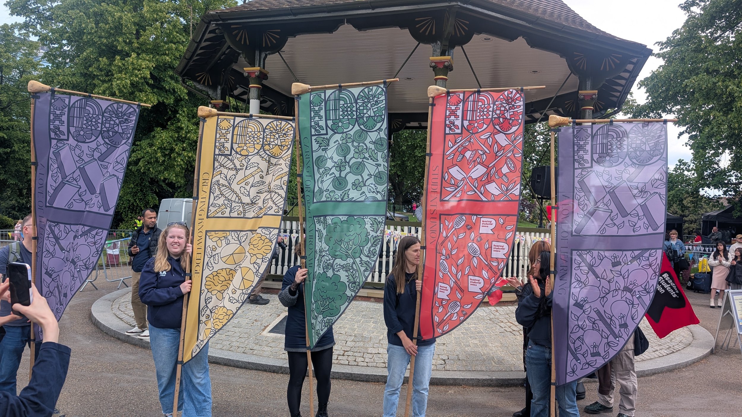 Reading university centenary celebrations where 5 students are holding 5 illustrated flags by Helen Ridley