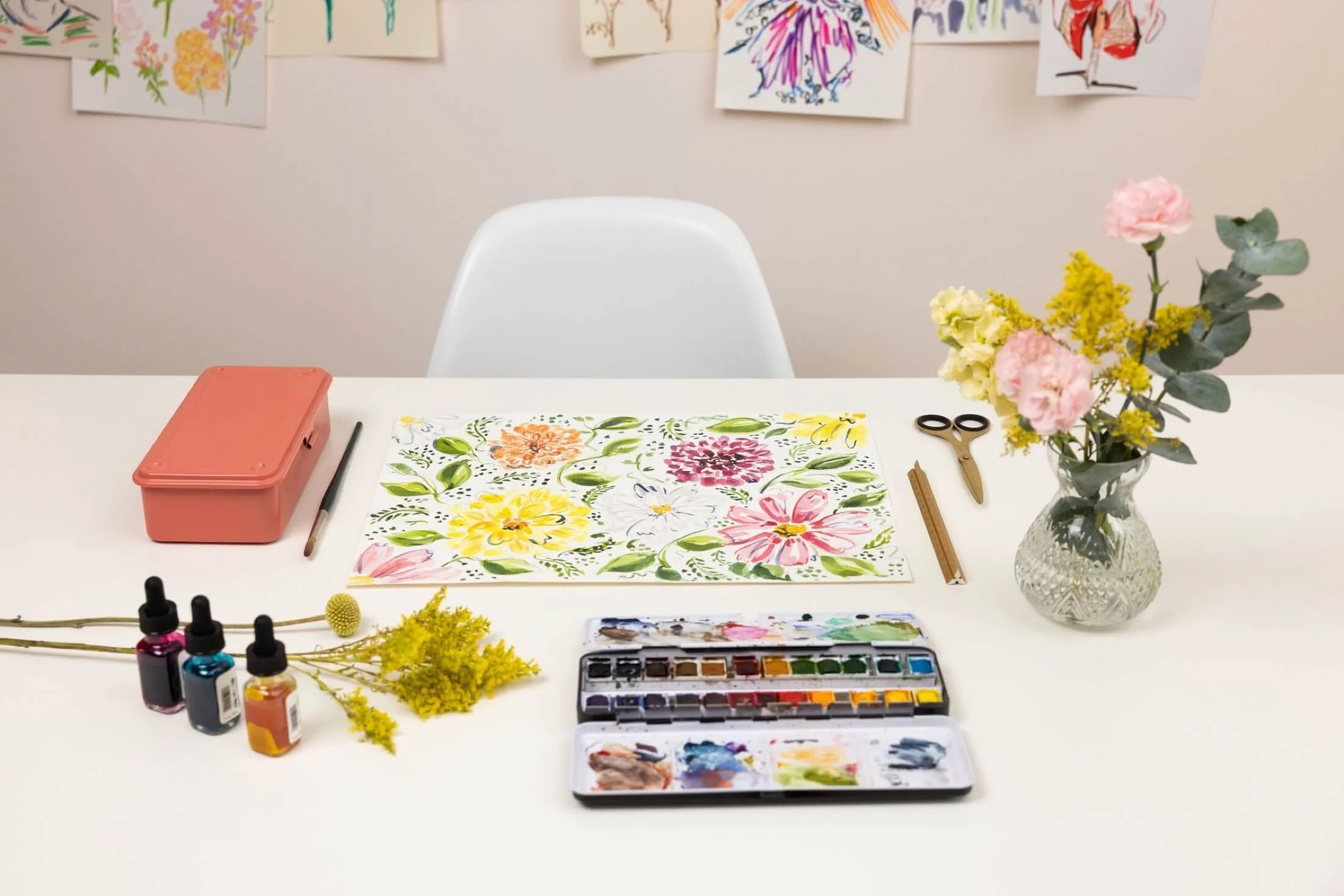 A white desk set with watercolour paints and other art equipment