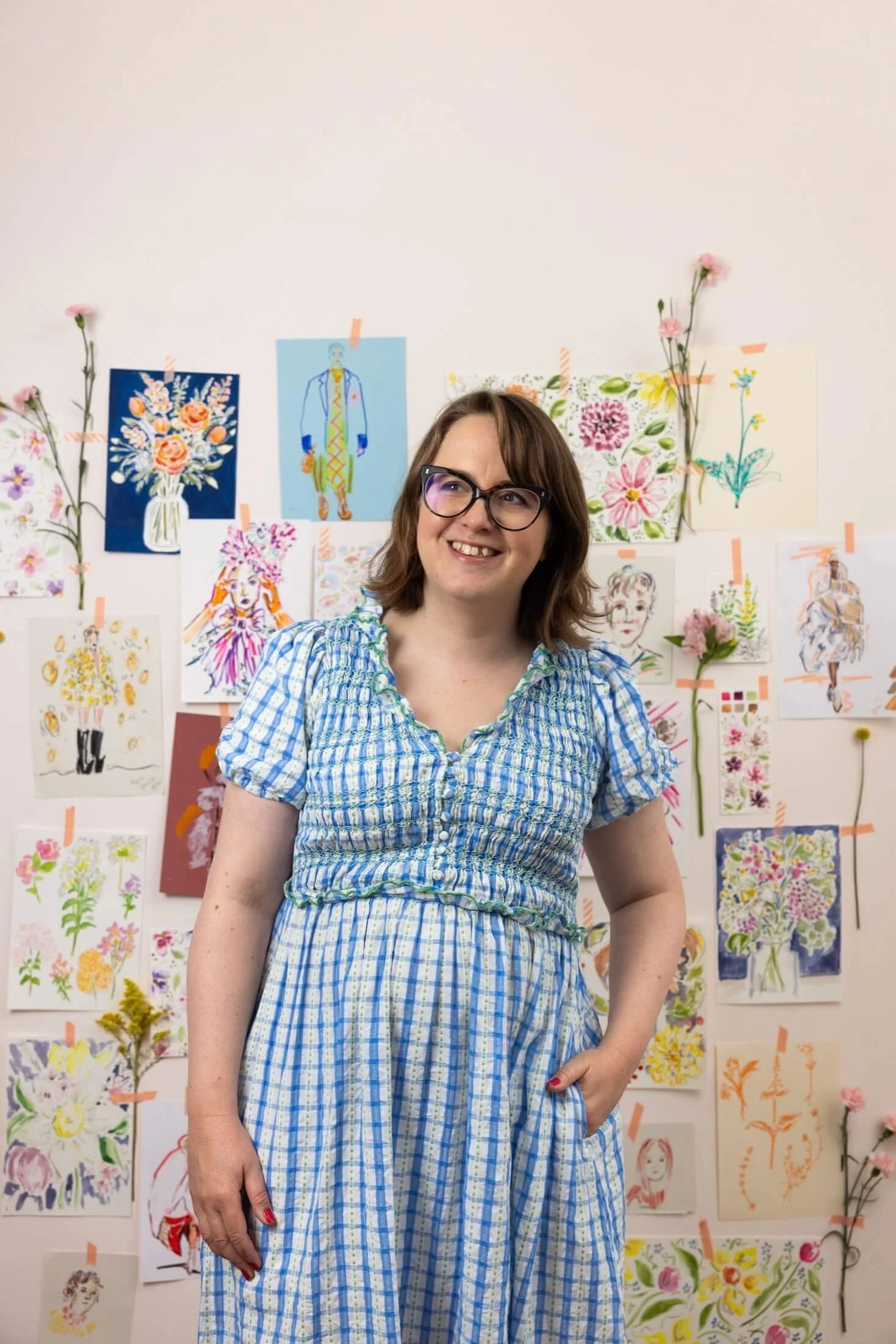 Helen Ridley stood proudly in front of a wall of her watercolour paintings and illustrations