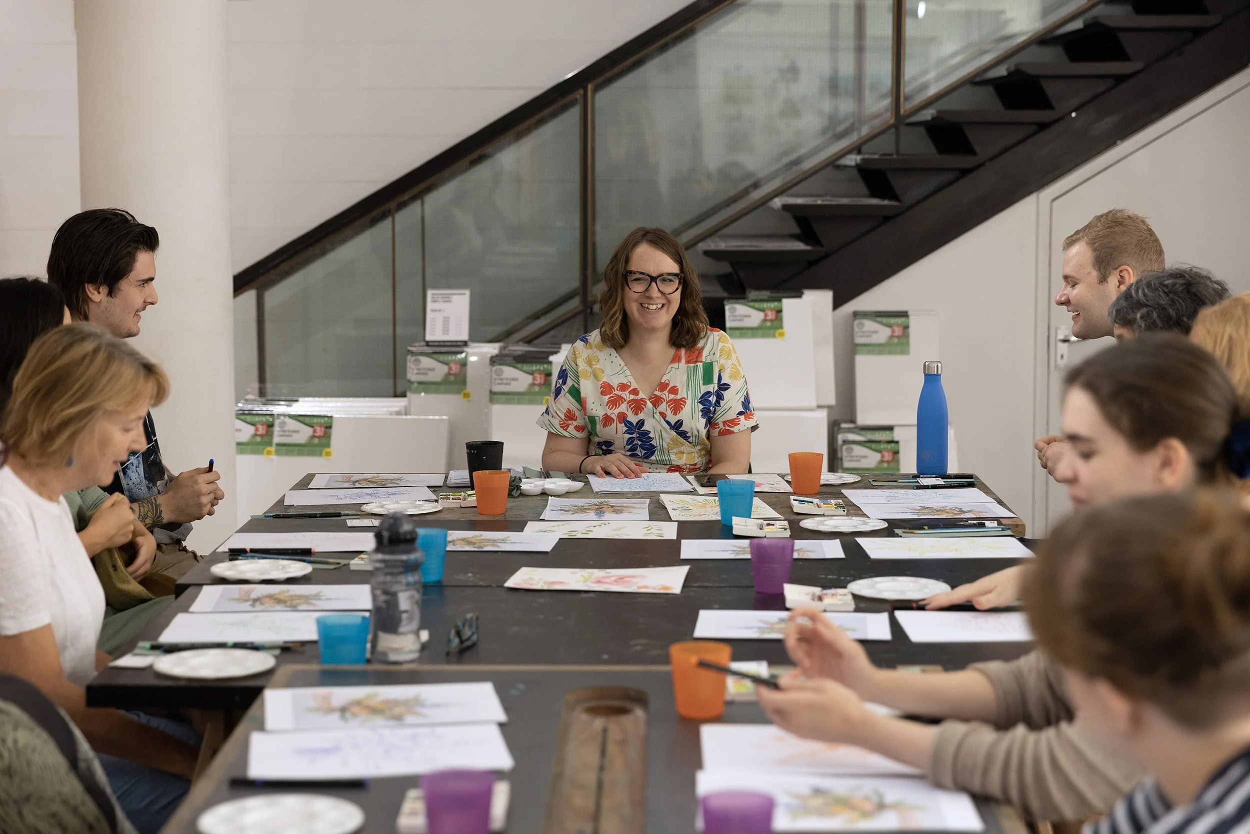 Illustrator Helen Ridley smiling and sat with watercolour workshop attendees