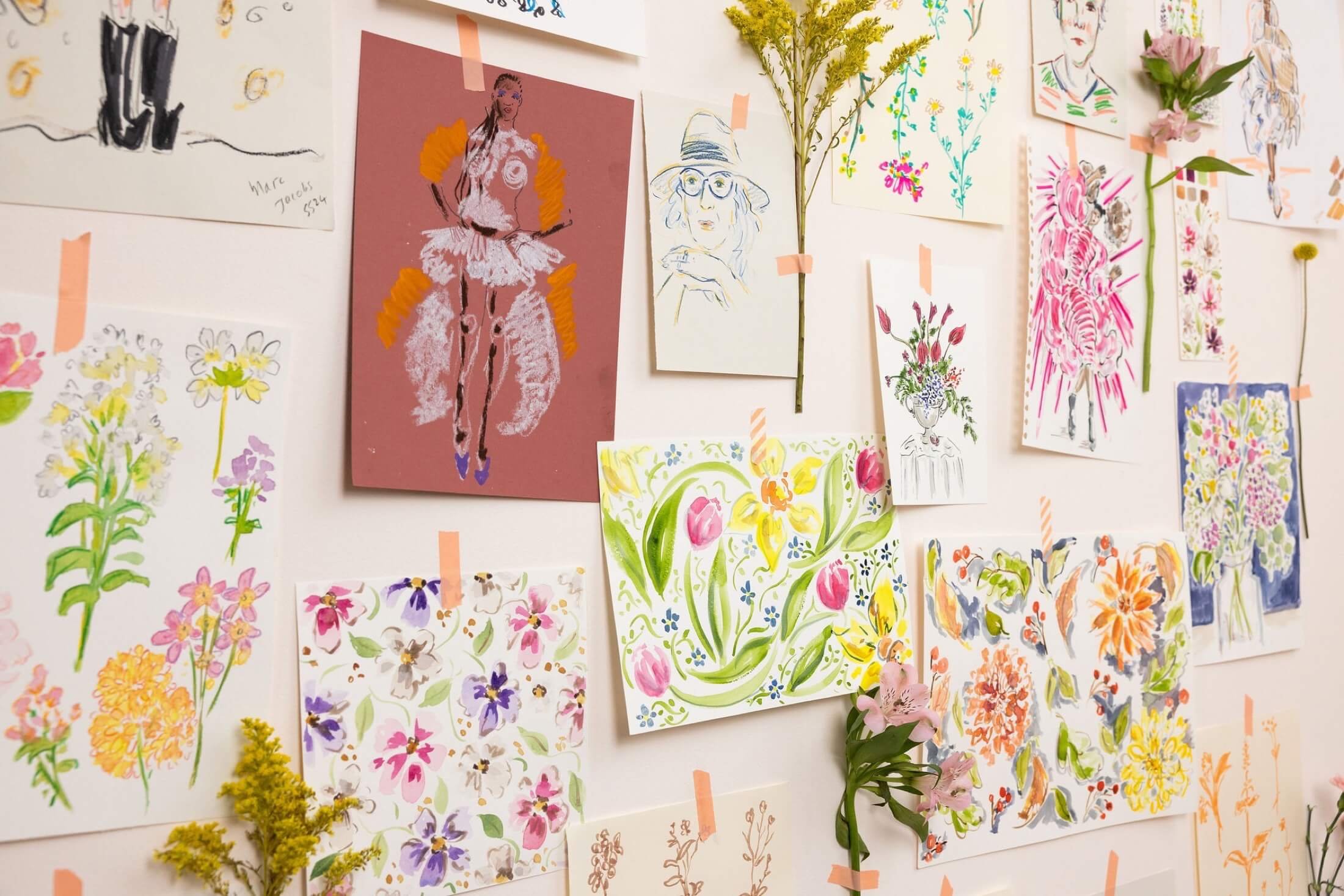 White wall with illustrations and flowers taped to it