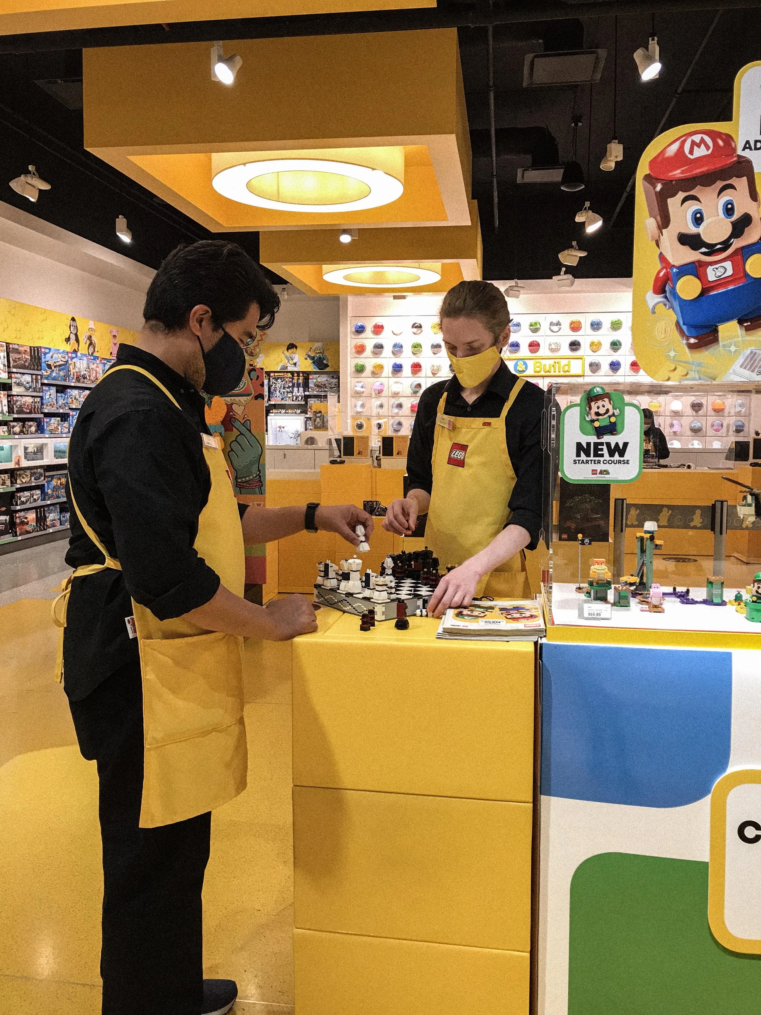 Photograph of Lego Store employees playing chess on a Lego Chess Set
