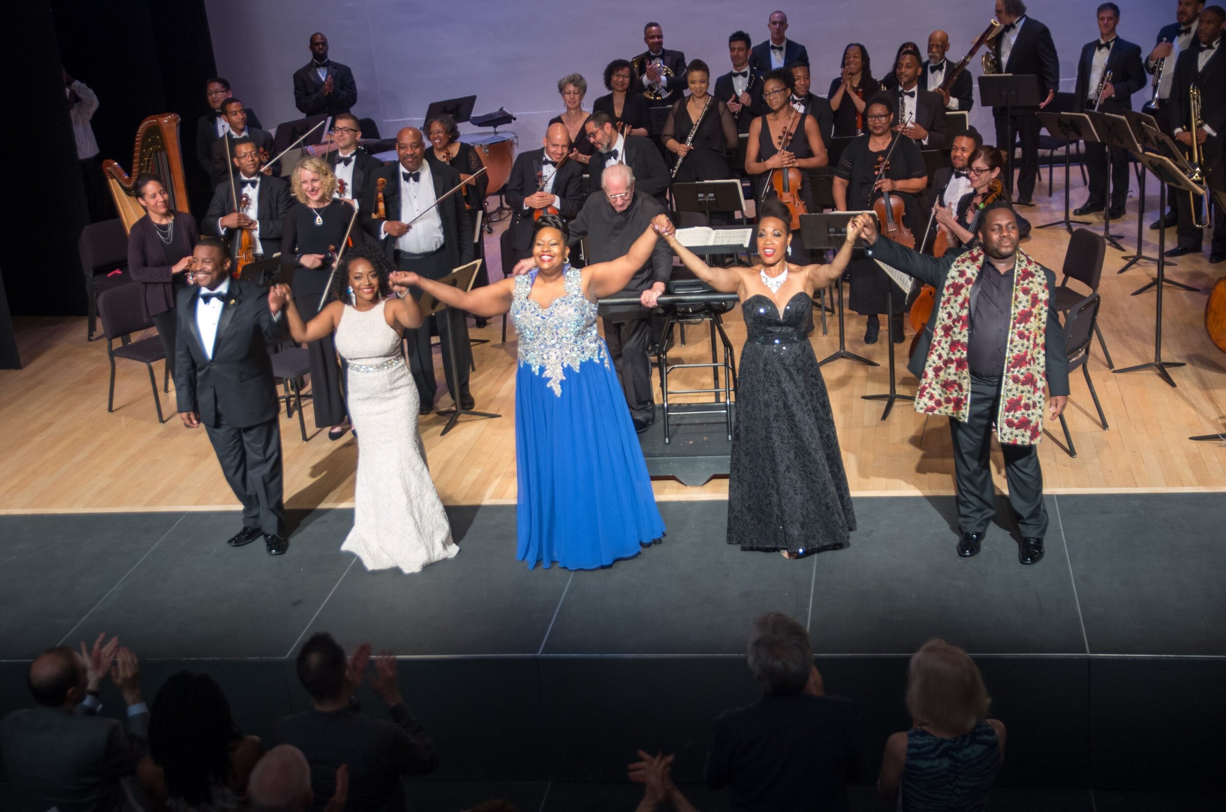 Tenor Chauncey Packer, soprano Brandie Sutton, mezzo-soprano Lucia Bradford, soprano Janinah Burnett, baritone Kenneth Overton, and conductor David Gilbert behind them, with orchestra.
Harlem Songfest Concert - June 1, 2018.