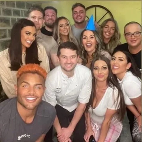 Group of people celebrating a birthday with party hats, smiling for the camera.