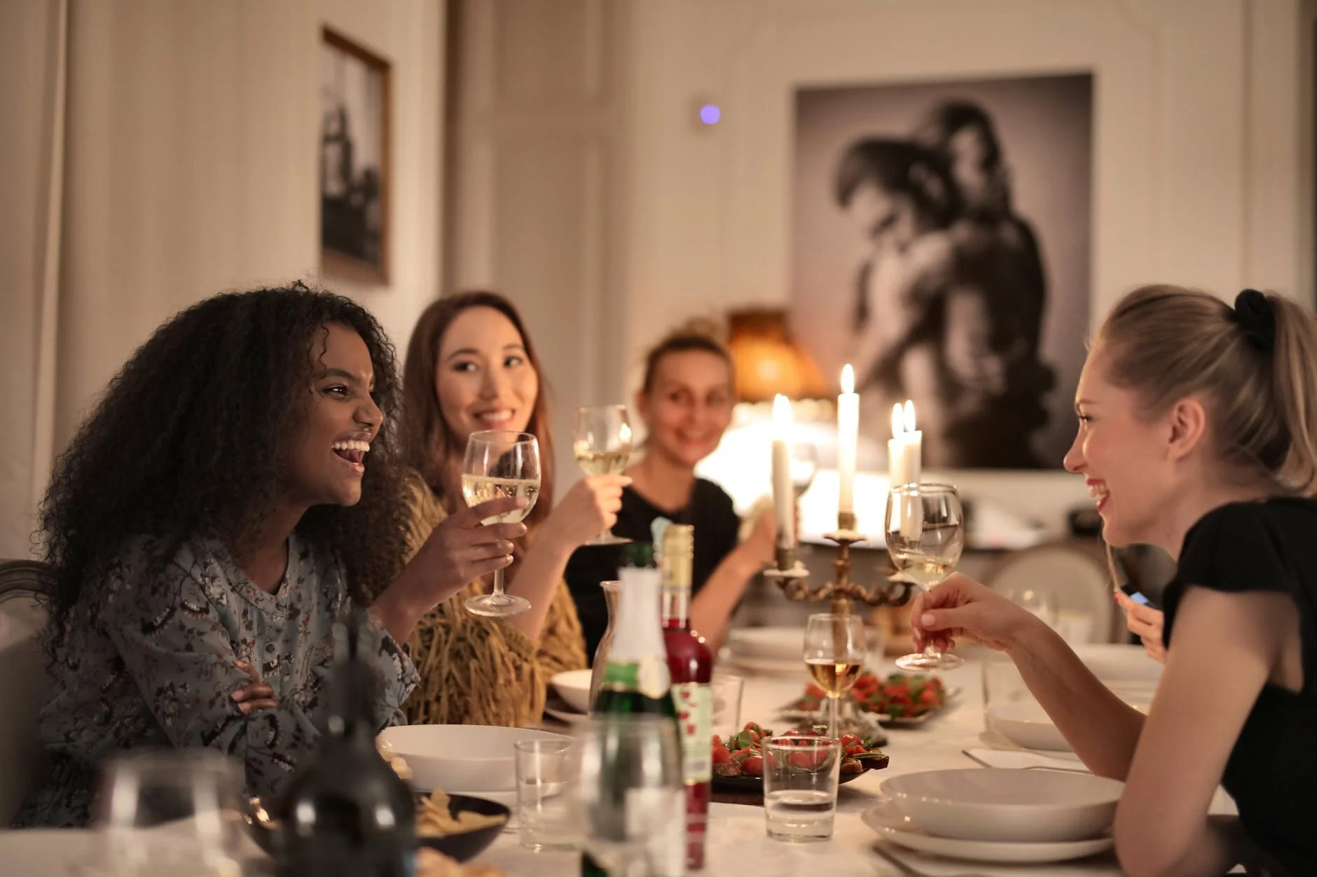 group of women having dinner toasting with wine glass in hand