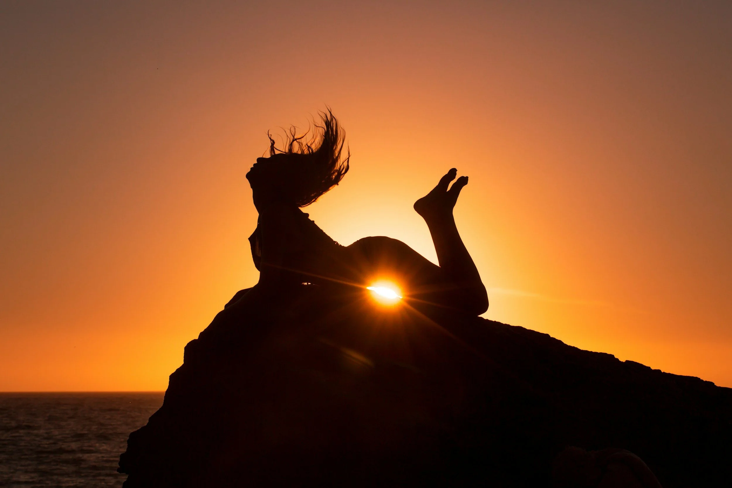 sunlight shining through under body fo woman on cliff during sunrise