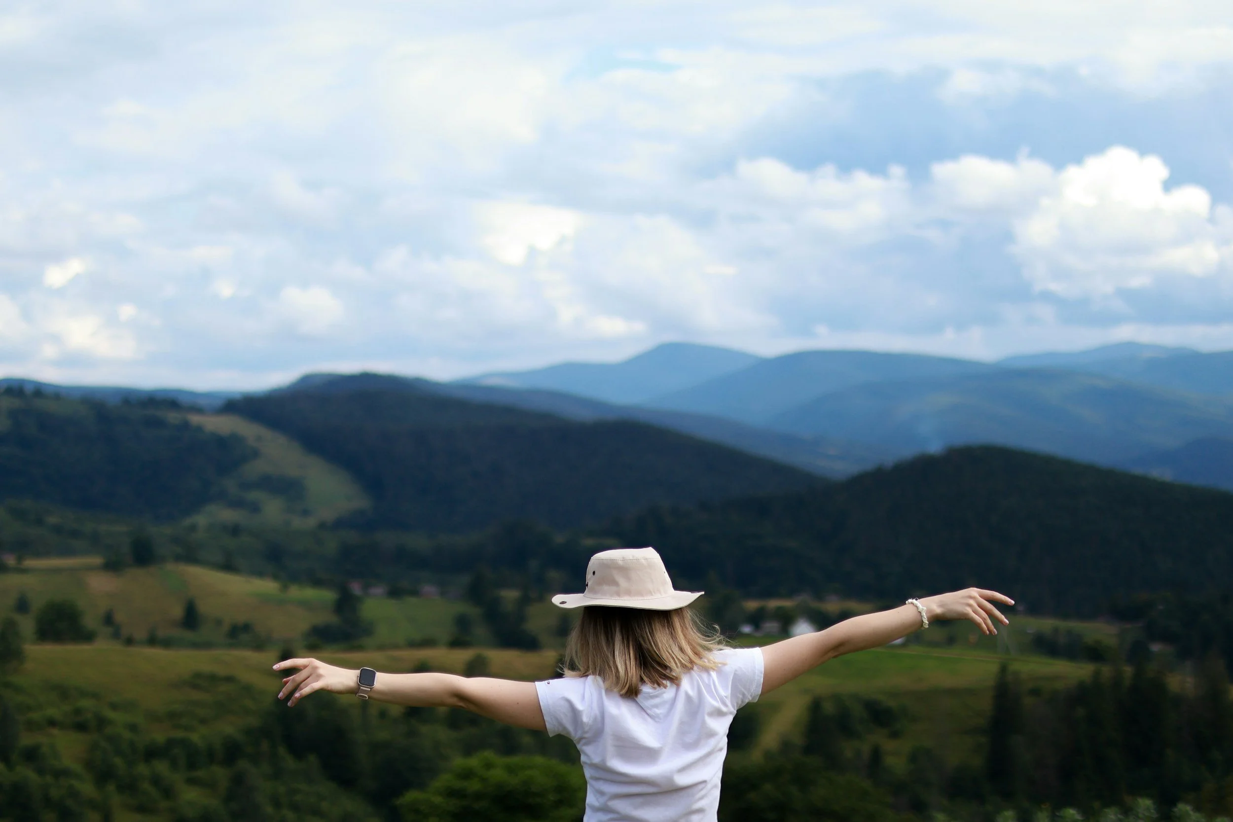 woman arms wide out overlooking valleys and hills freedom