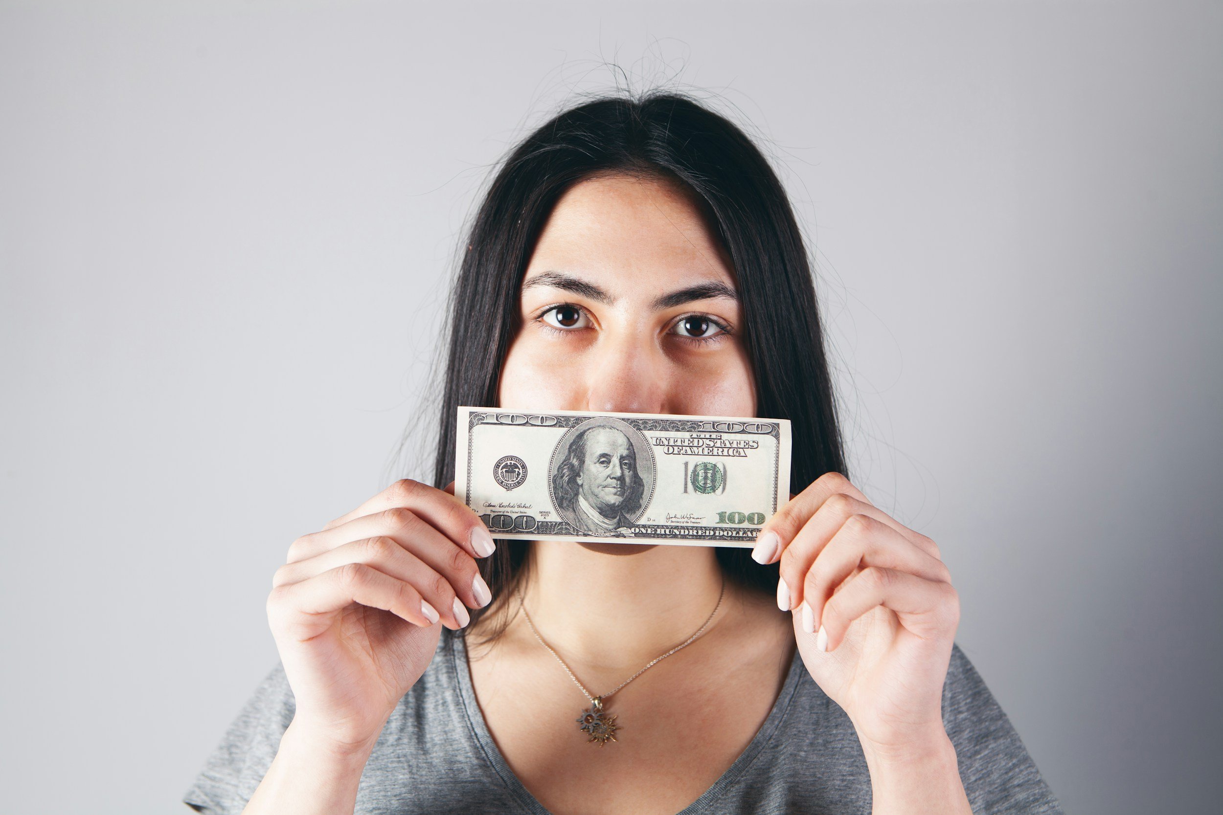 money stress woman holding hundred dollar bill in hands