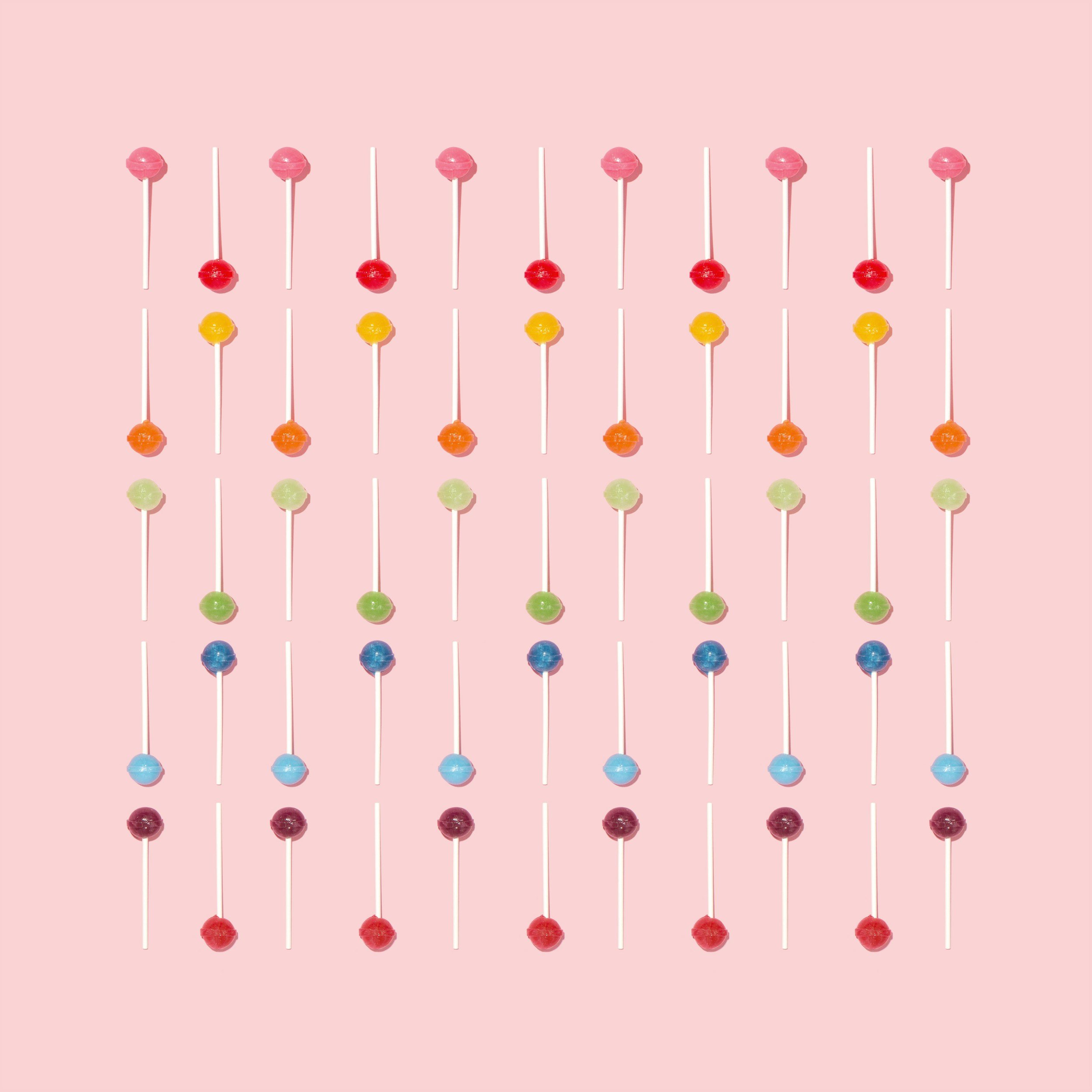 candy lollipops in ranging colors against pink background