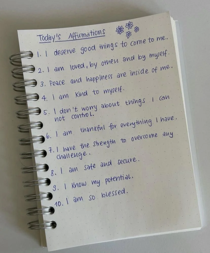 daily affirmations listed out in wrriting on dotted sheet of paper in blue ink