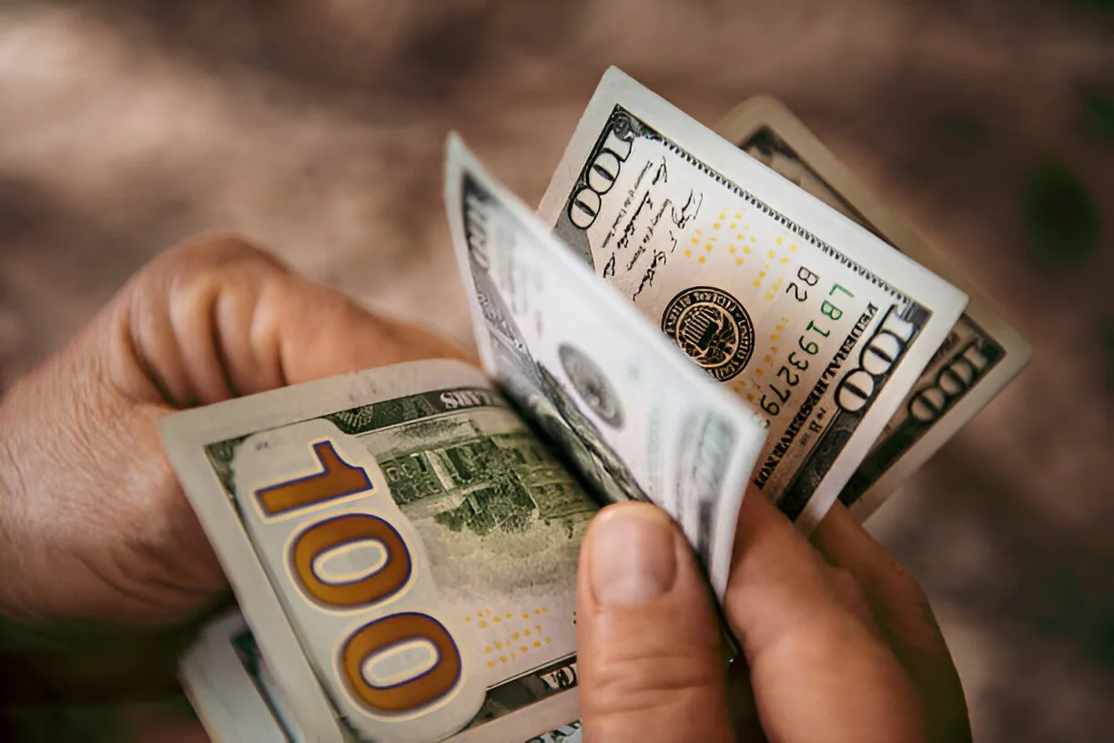 hand holding and flipping through hundred dollar american bills