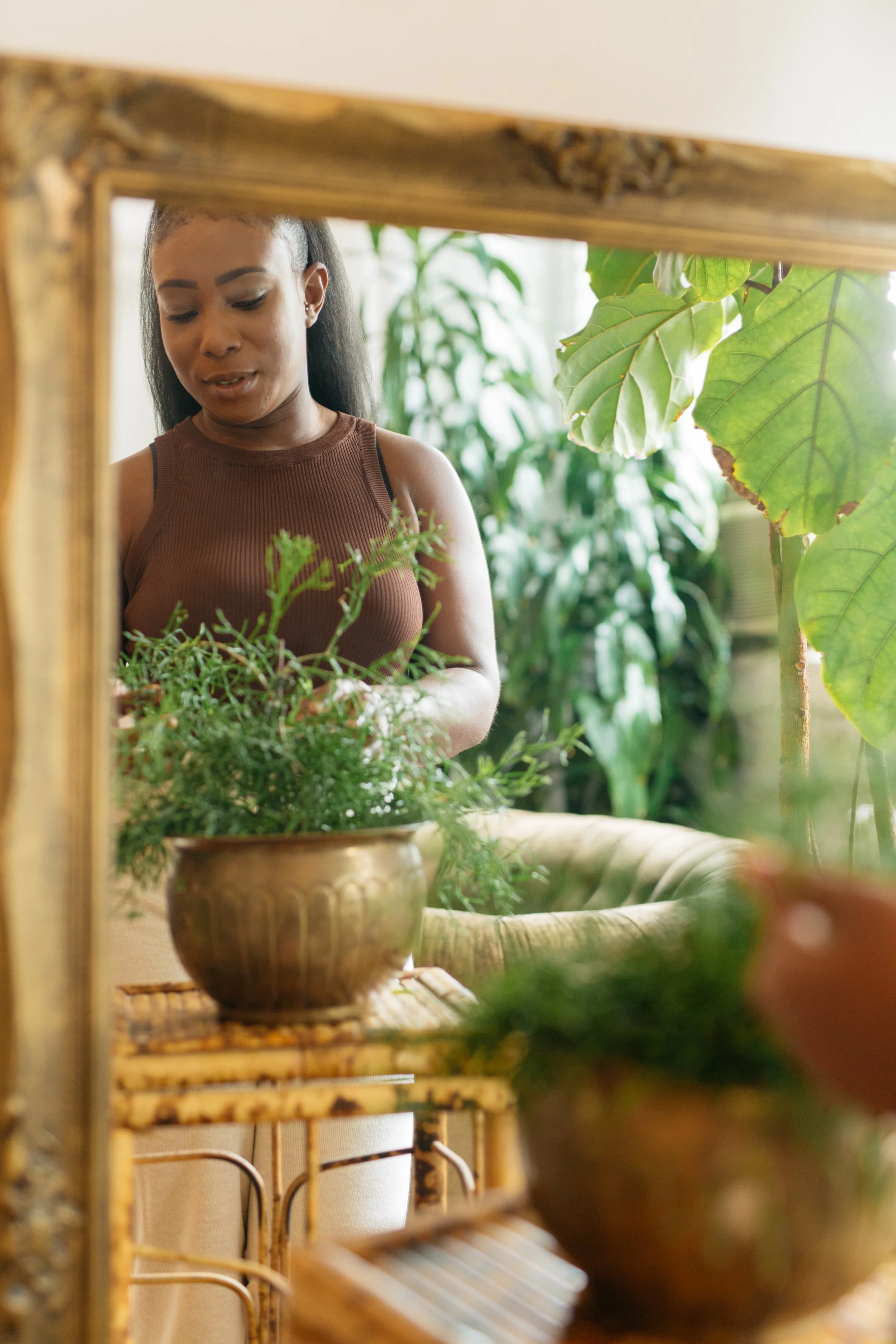 Image of Morgan Blackman in gold rimmed mirror tending to a plant