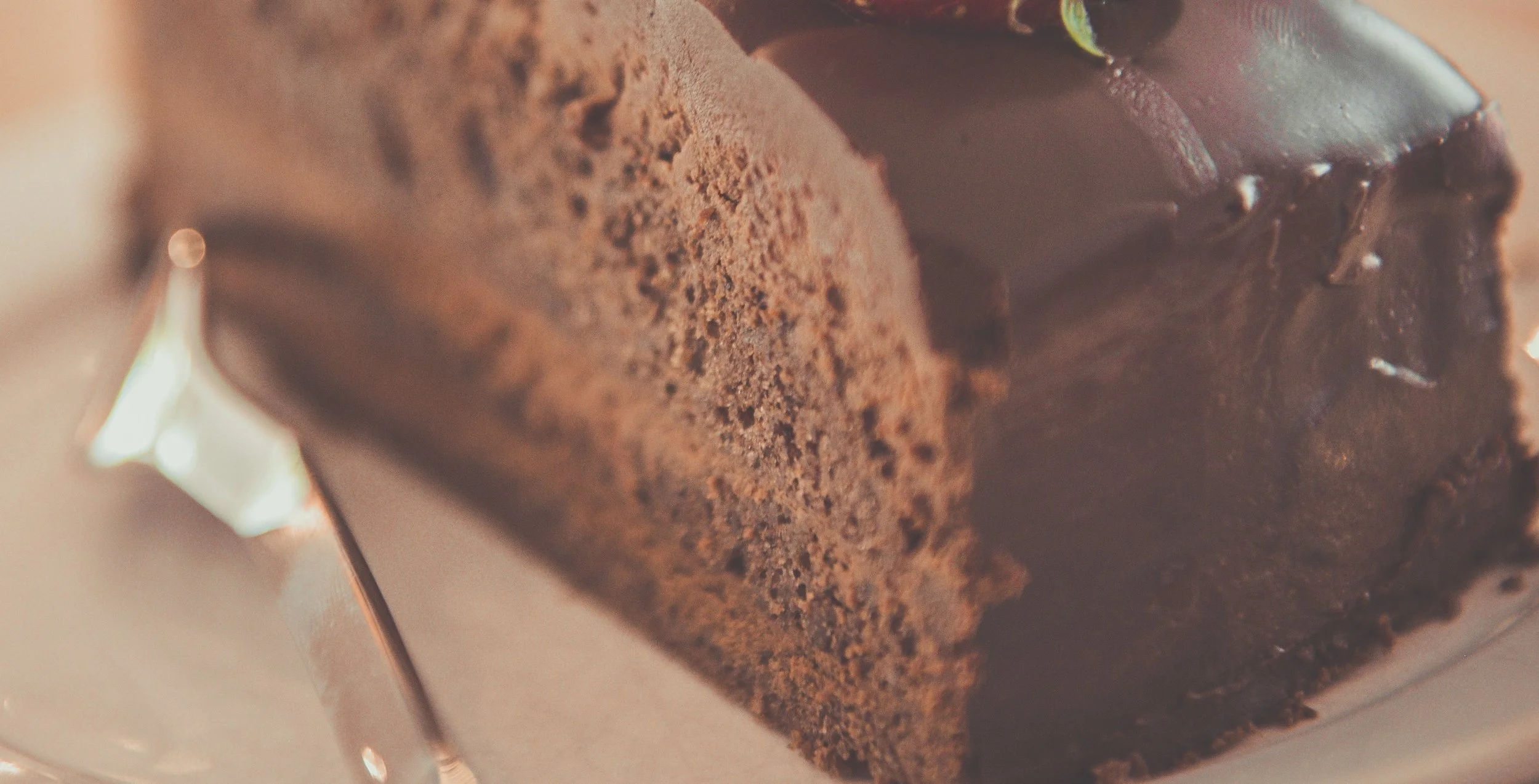 A piece of chocolate cake on a plate with a strawberry on top,