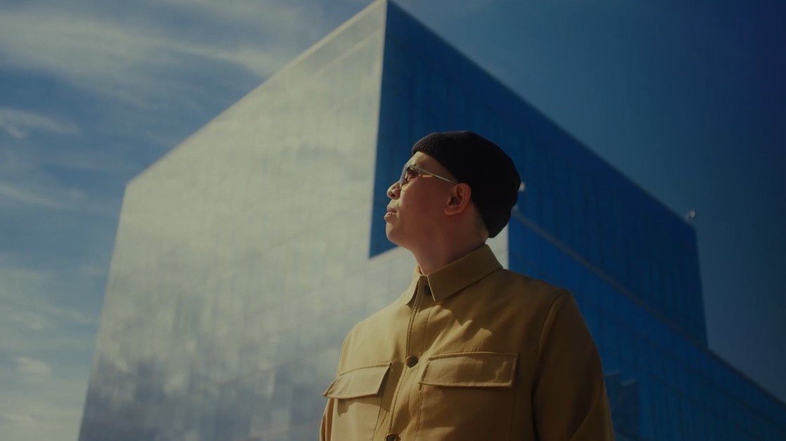 Man standing looking towards sun in front of abstract building, The Kiln video production