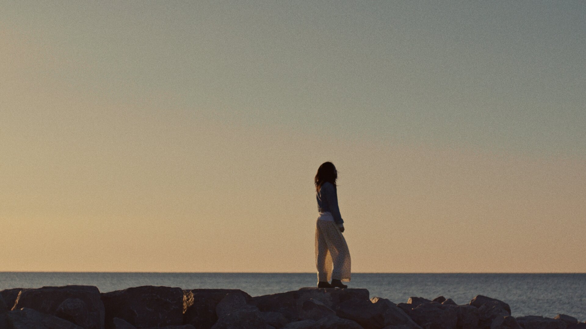 Girl looks out to ocean, scene from The Kiln video production