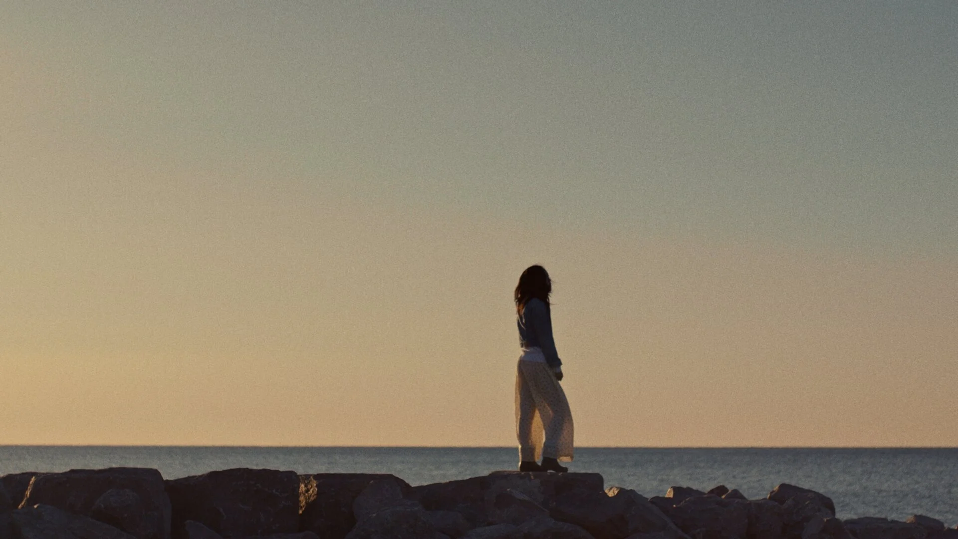 Girl looks out to ocean, scene from The Kiln video production