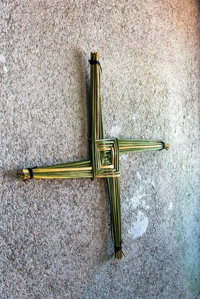 a green, woven st brigid's cross on a carpet floor