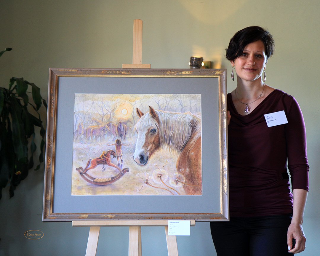 An artist stands beside her framed painting of a horse in a twilight scene with other horses in the background, a girl playing with a rocking horse, and a large white flower in the foreground.