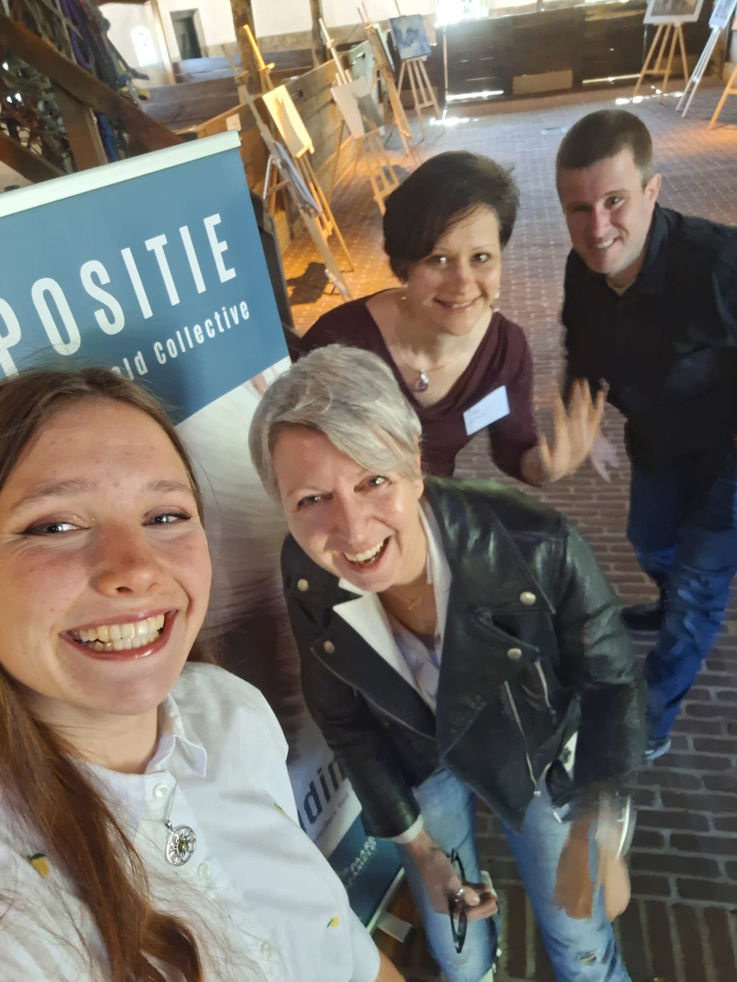Group of five people smiling at a conference or event with a sign that reads 'POSITIVE world collective'.