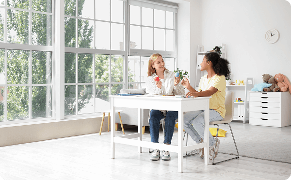 Psychologist meets with a child at a table in a bright therapy office, using colorful tools to support child and teen psychology care.