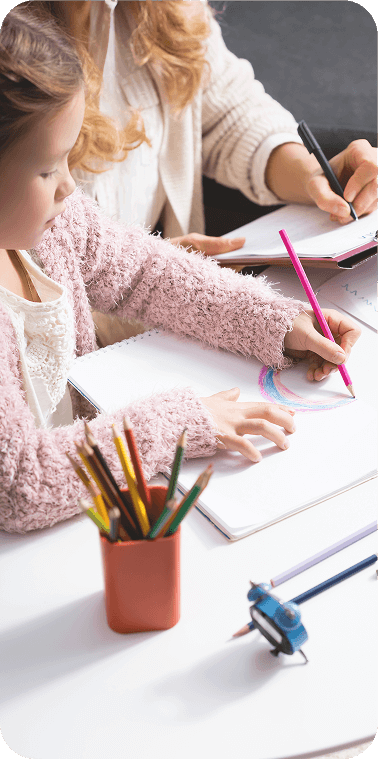 Child completes a drawing while a psychologist takes notes beside them, showing a focused assessment session.