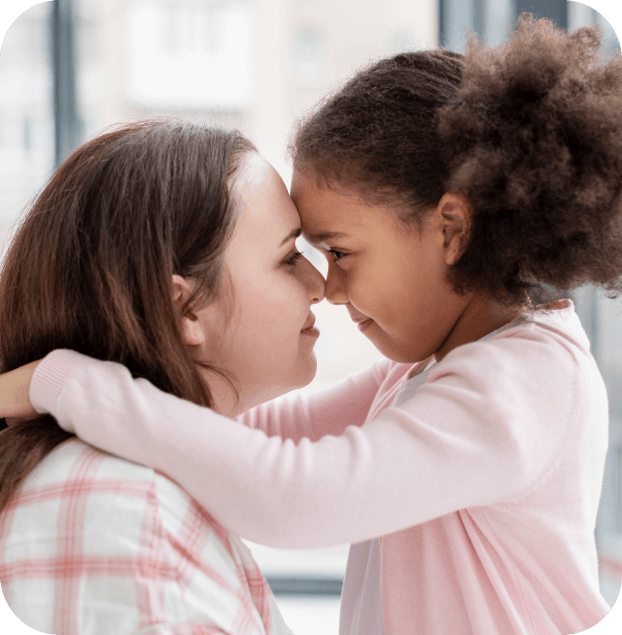 Caregiver and young child share a close, reassuring moment with foreheads touching, showing trust and emotional connection.