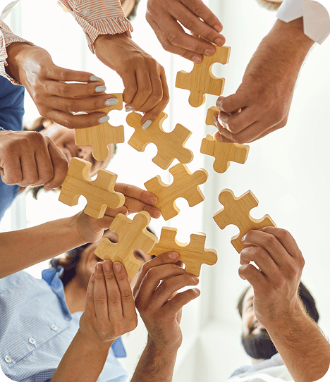 Hands hold wooden puzzle pieces coming together, symbolizing collaboration and shared expertise. The image represents a team of Toronto child psychologists working together to support children and families with care and confidence.