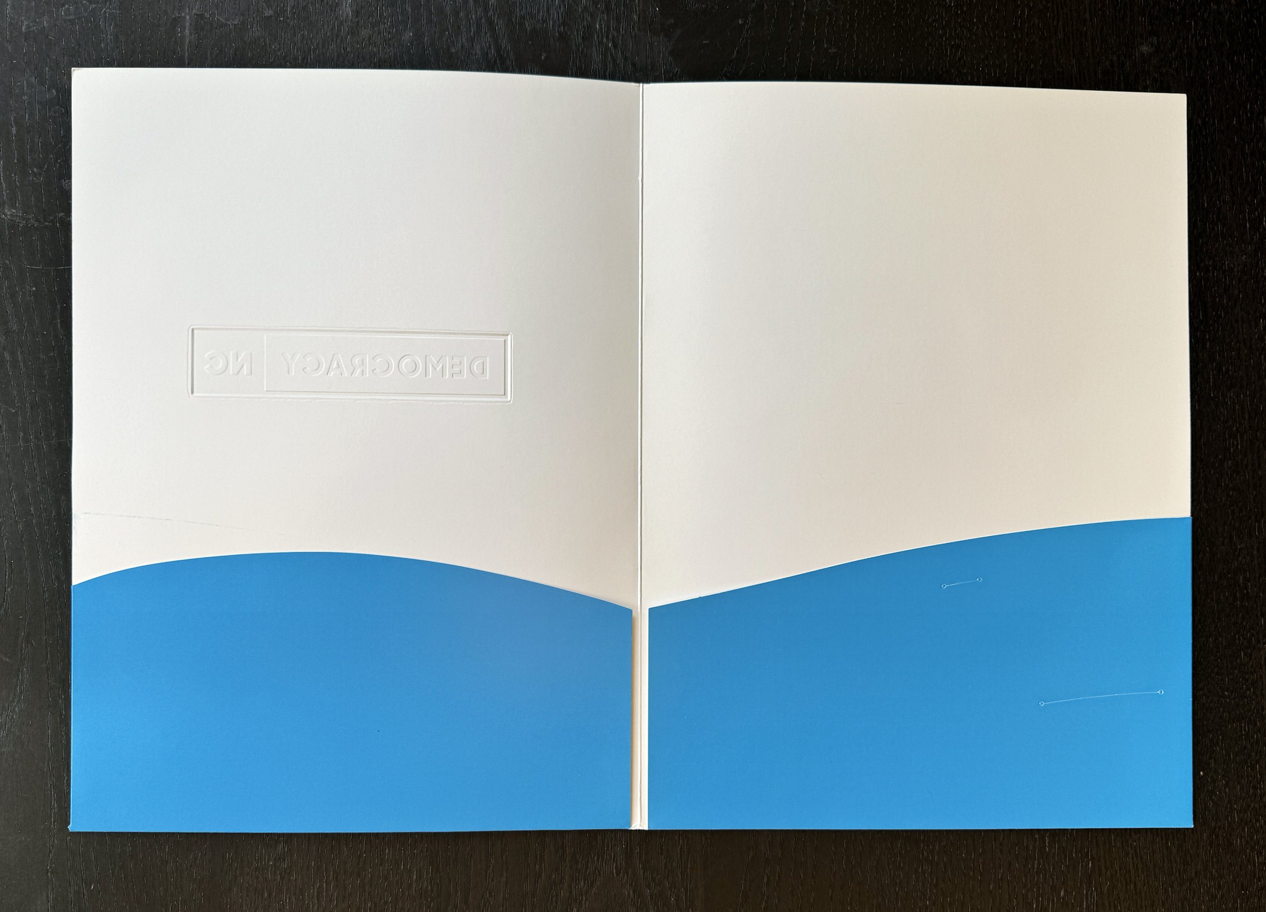Pocket folder with fun curved pockets and reveal of inverse of blind embossed cover