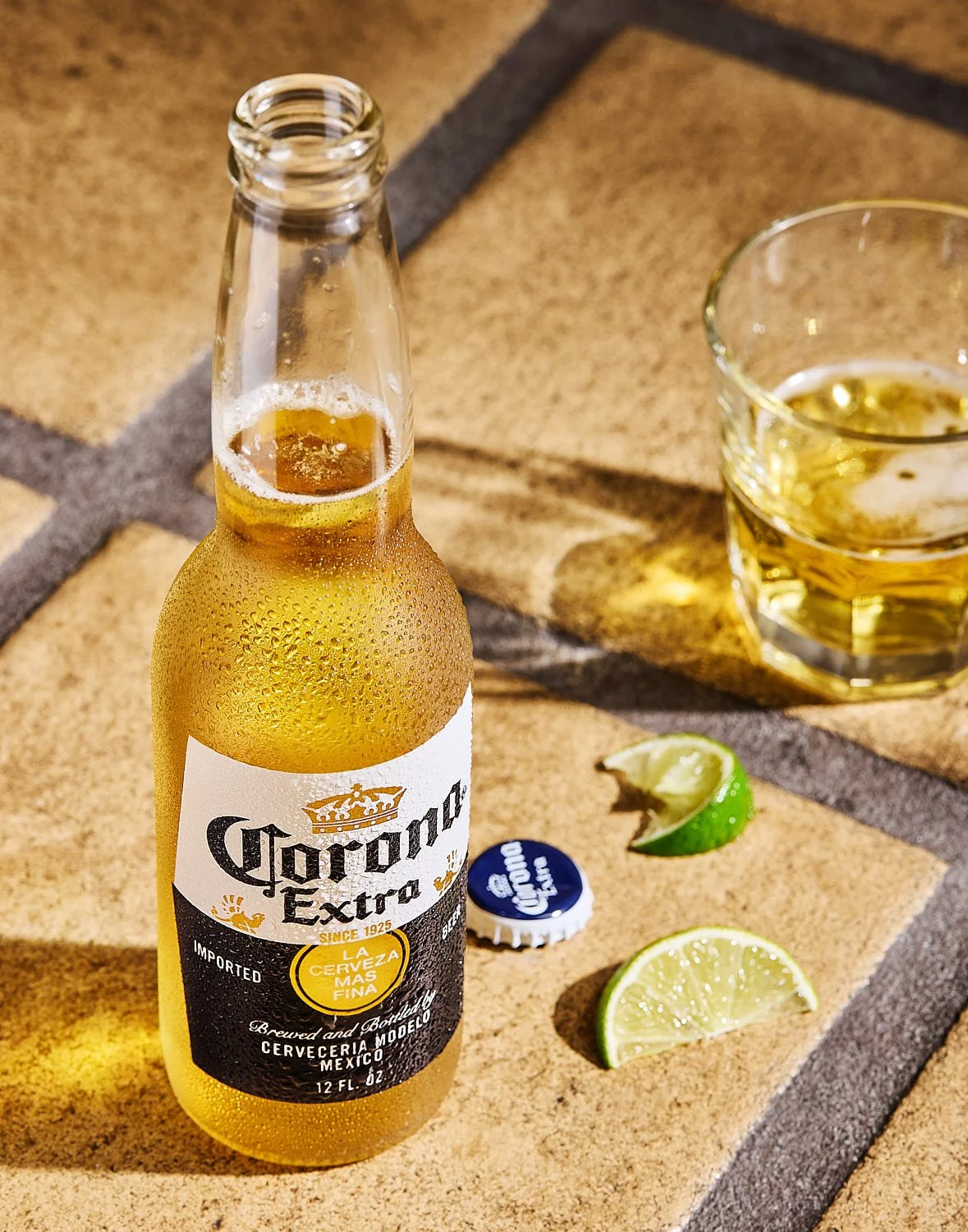 Bottle of a frosty cold Corona Beer with a couple of lime wedges and a half glass of freshly poured beer. Beverage photography by Seattle drink photographer Mike Gluckman.