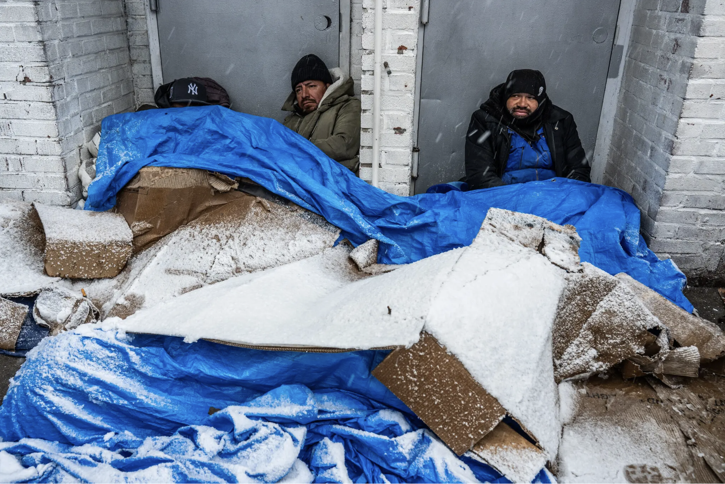 On a sidewalk in Queens, several men sat in the recesses of shallow doorways, blanketing themselves with blue tarps and flattened cardboard boxes to keep out the cold as the snowfall grew heavier.

One of the men, Elioth Gonzalez, 41, a former forkli
