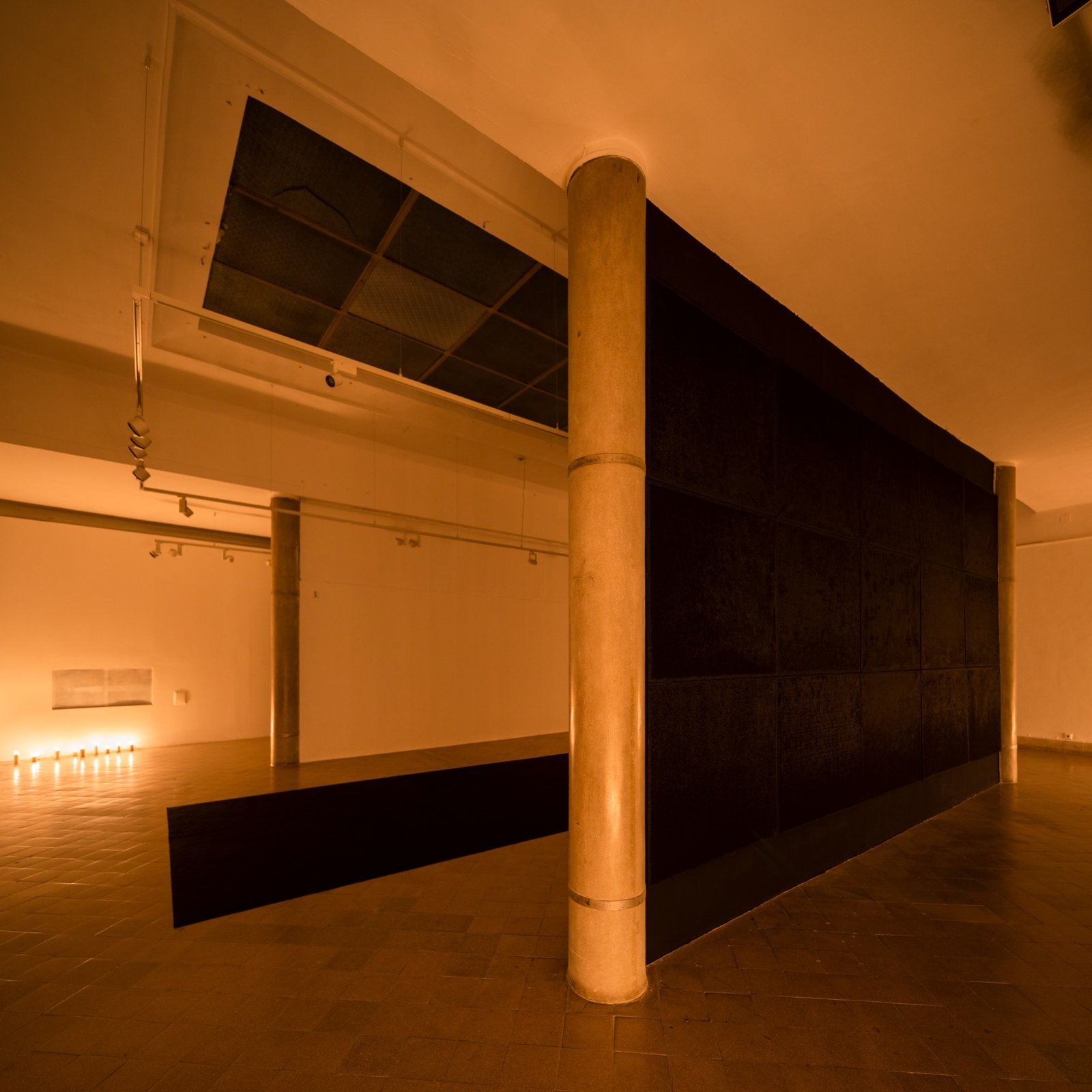 Oblique view of sculptural black wall intersecting open gallery space – "Gazing into Darkness" by Gábor Koós.