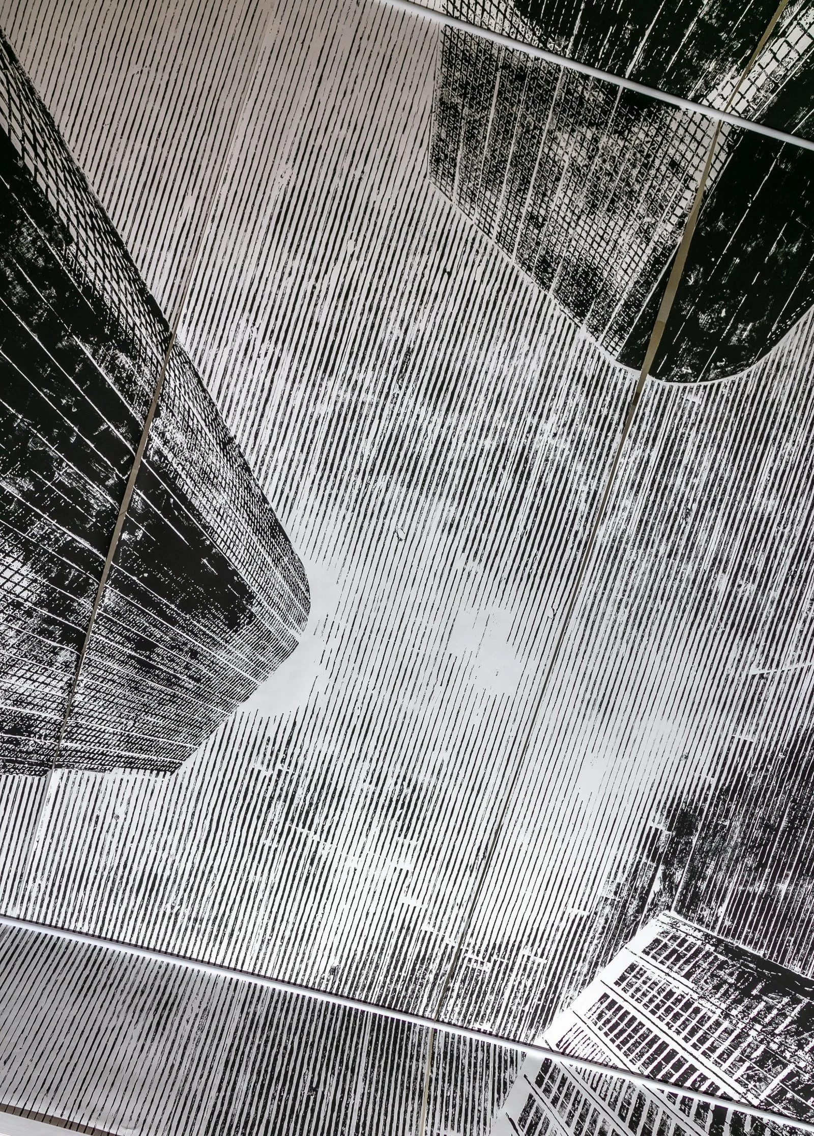 Black and white woodcut panels depicting skyscrapers printed on canvas for ceiling installation by Gábor Koós.